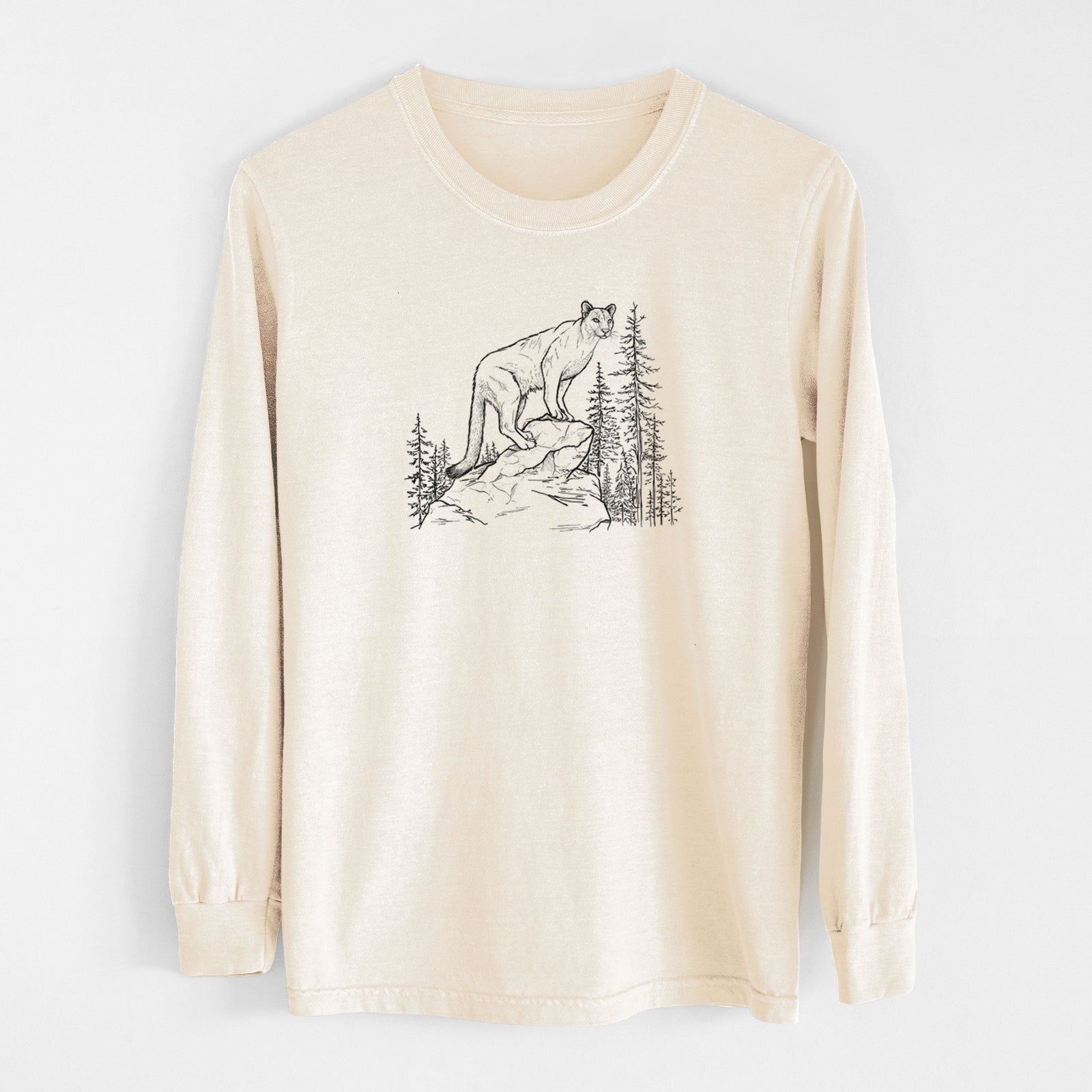 Ivory Comfort Colors long sleeve shirt laid flat, printed with a black ink illustration of a mountain lion standing on a rocky ledge among pine trees.