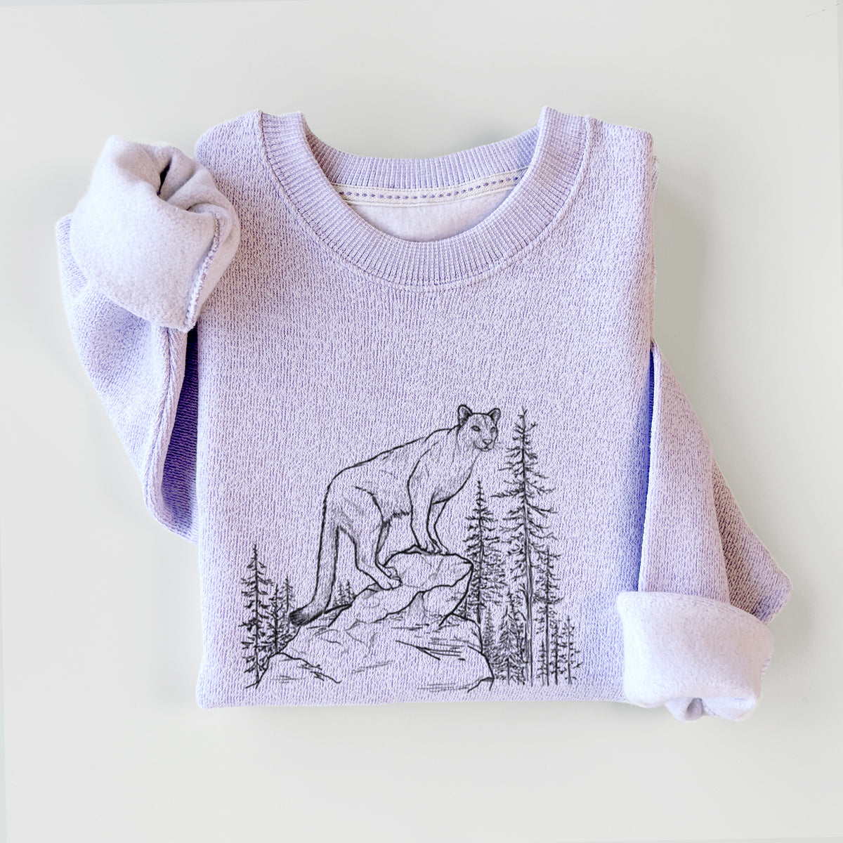 Ice purple knit sweatshirt printed with a black ink illustration of a mountain lion standing on a rocky ledge among pine trees, styled flat.