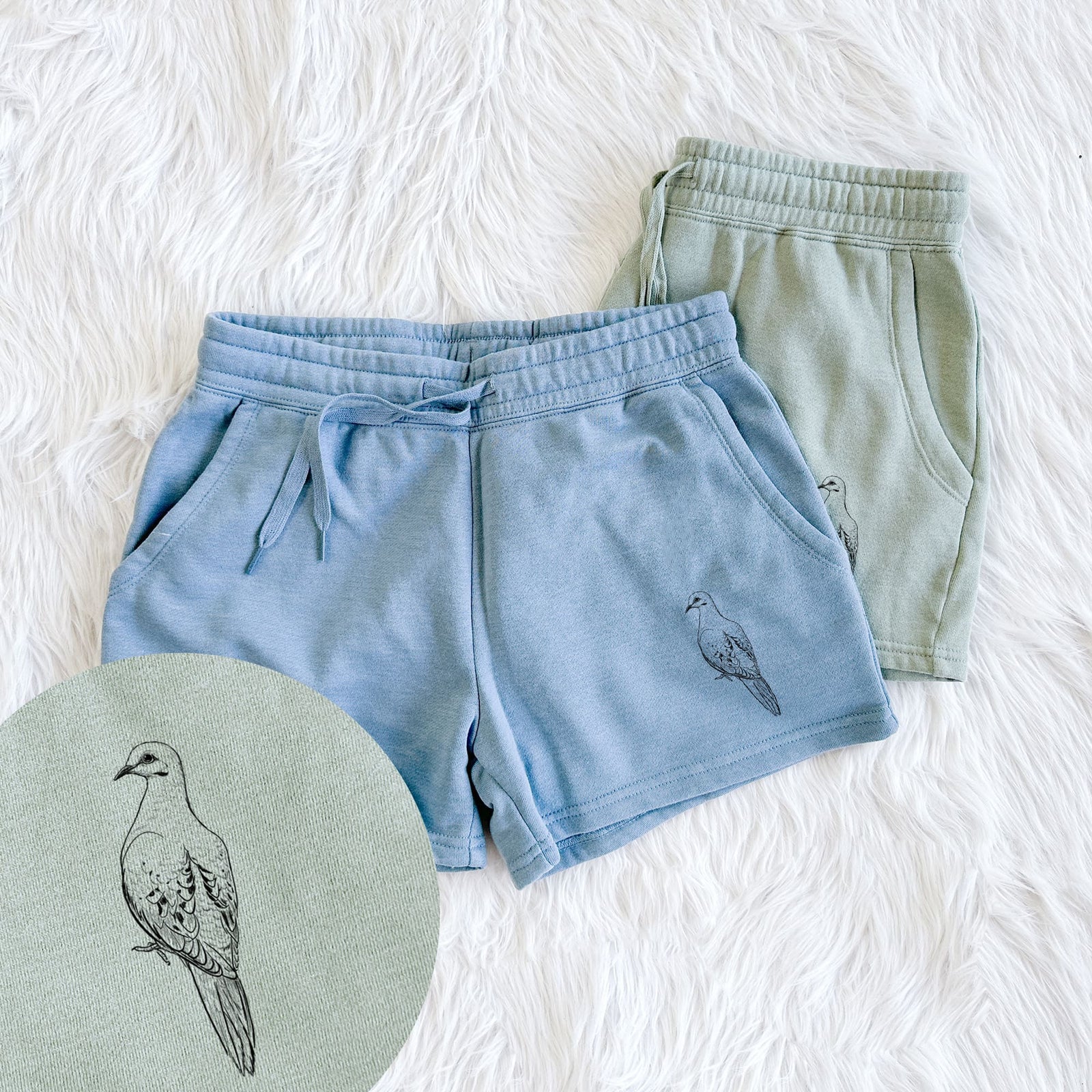 Two pairs of Cali Wave shorts in different colors printed with a detailed black ink sketch of a mourning dove perched, with a close-up of the print.