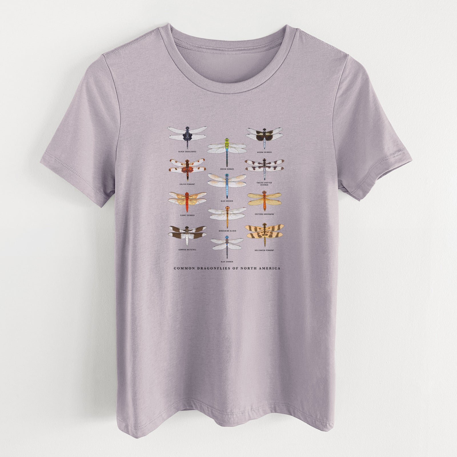 Light violet women's relaxed fit cotton t-shirt laid flat, printed with a full-color chart of North American dragonflies, each labeled with its species.