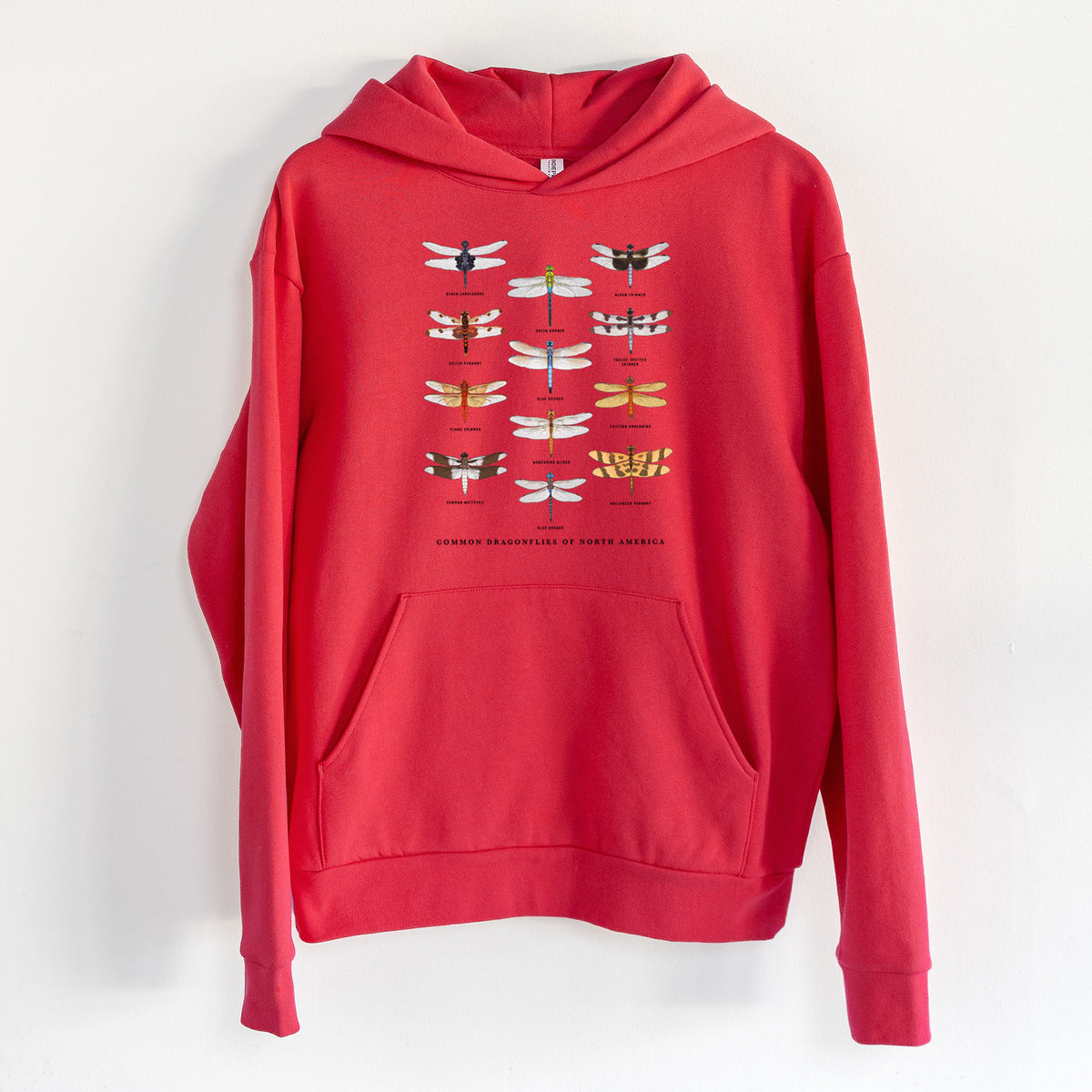 Common Dragonflies of North America - Statement Midweight Hoodie in Cherry Red, hanging on a white wall, with a front kangaroo pocket and no drawcords.