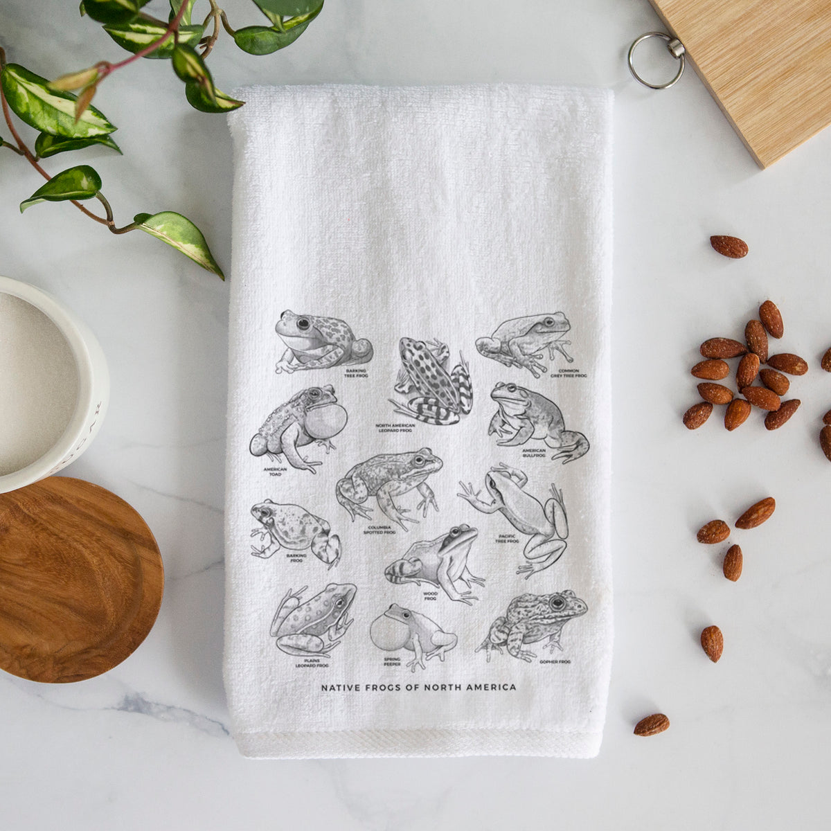 White hand towel printed with a chart of black ink illustrations of North American frog species.