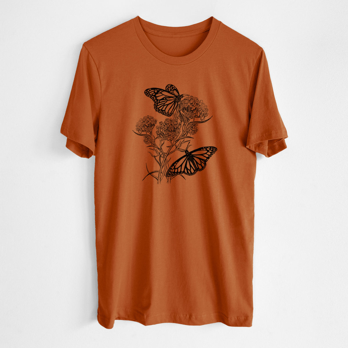 Autumn lightweight cotton t-shirt laid flat, printed with a black ink illustration of two monarch butterflies on flowering milkweed.