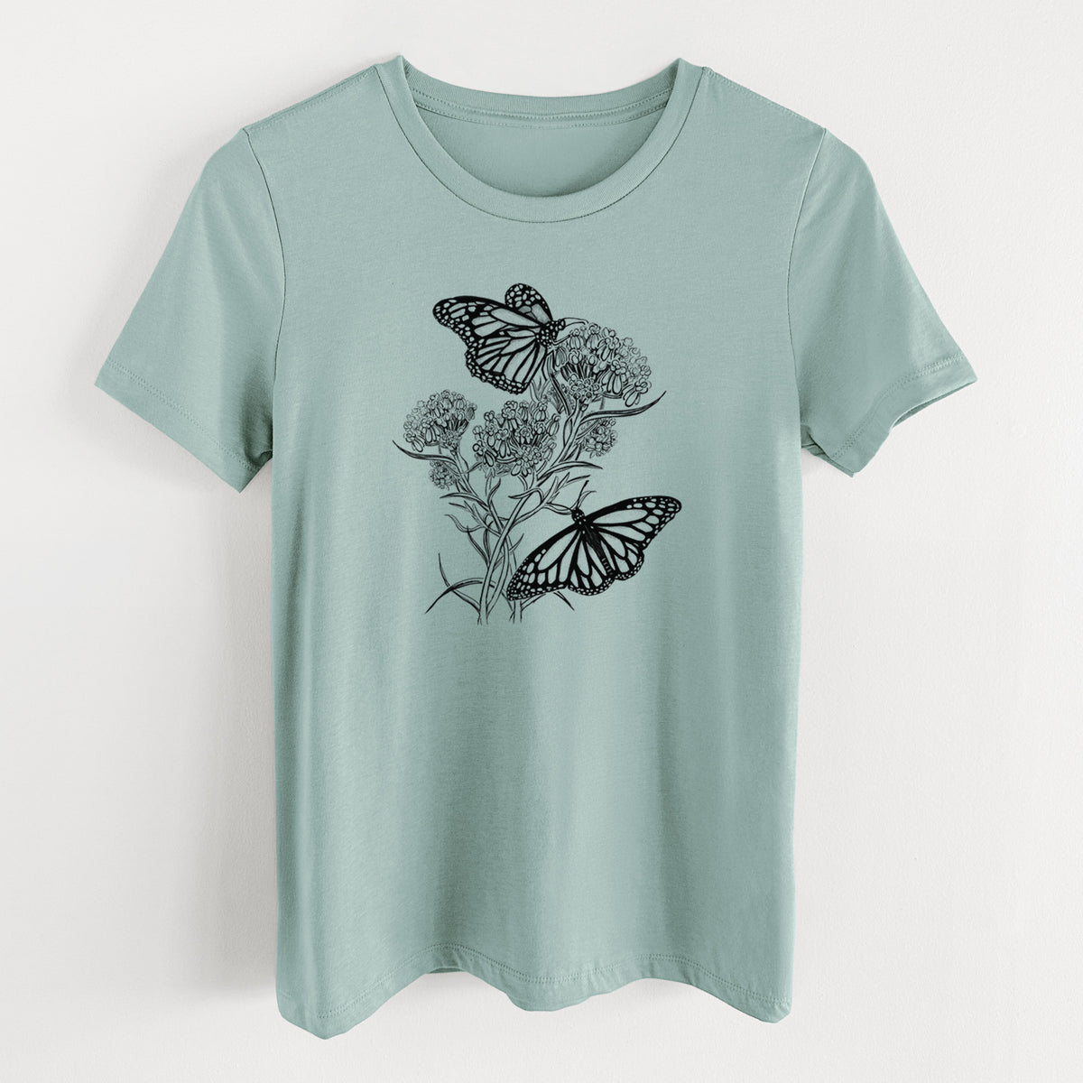 Dusty blue women's relaxed fit cotton t-shirt laid flat, printed with a black ink illustration of two monarch butterflies on flowering milkweed.