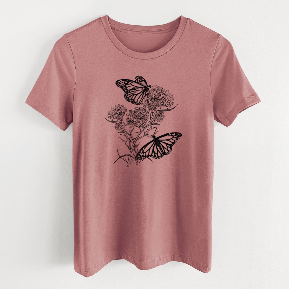 Mauve pink women's relaxed fit cotton t-shirt laid flat, printed with a black ink illustration of two monarch butterflies on flowering milkweed.
