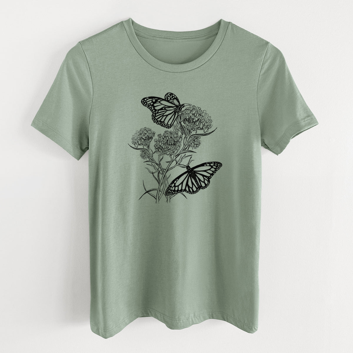 Sage green women's relaxed fit cotton t-shirt laid flat, printed with a black ink illustration of two monarch butterflies on flowering milkweed.