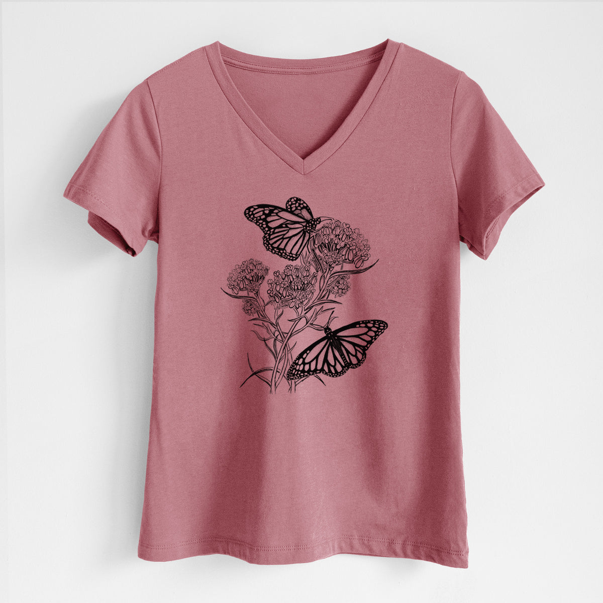 Mauve pink women's relaxed fit cotton V-neck t-shirt laid flat, printed with a black ink illustration of two monarch butterflies on flowering milkweed.