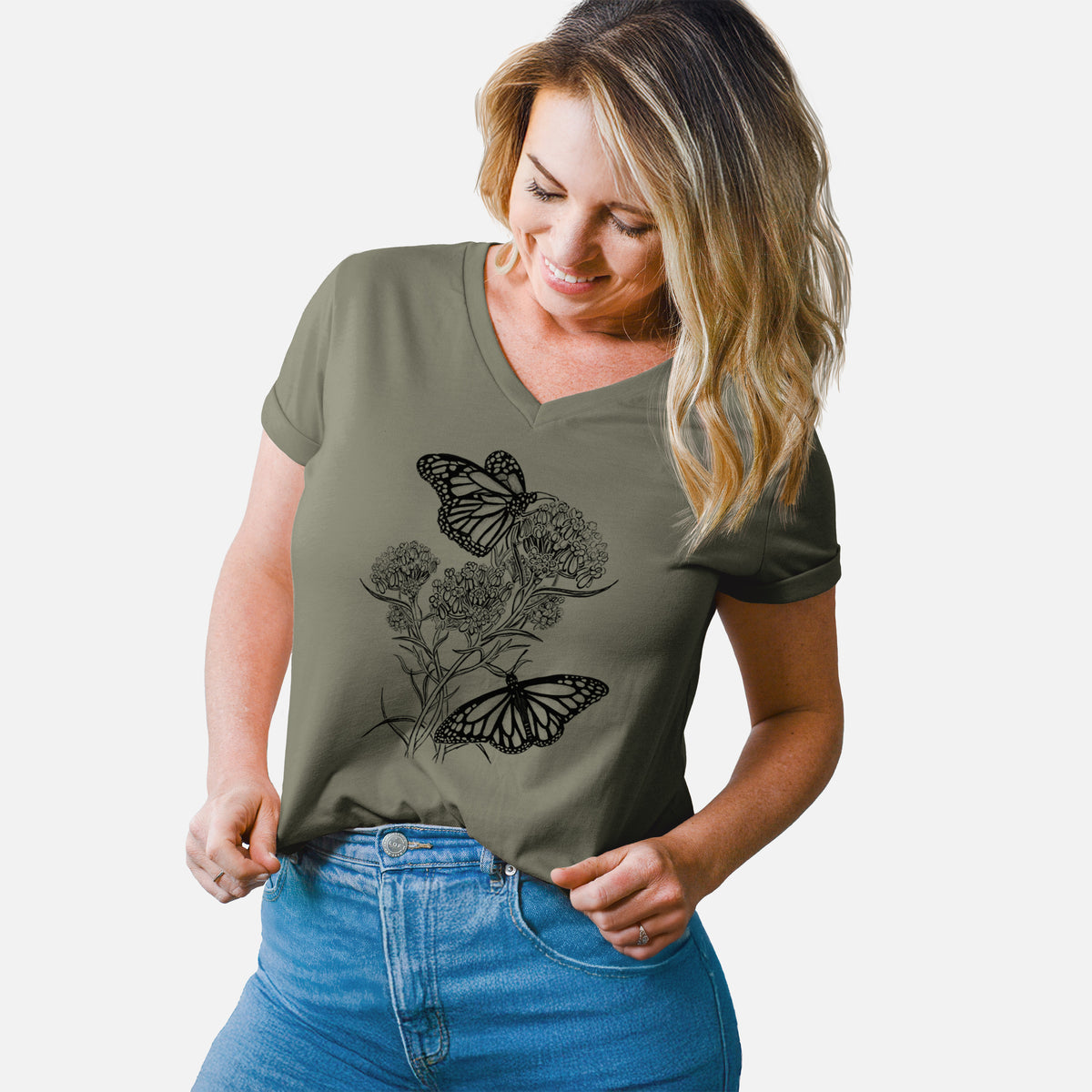 Woman wearing a military green women's relaxed fit cotton V-neck t-shirt printed with a black ink illustration of two monarch butterflies on flowering milkweed.