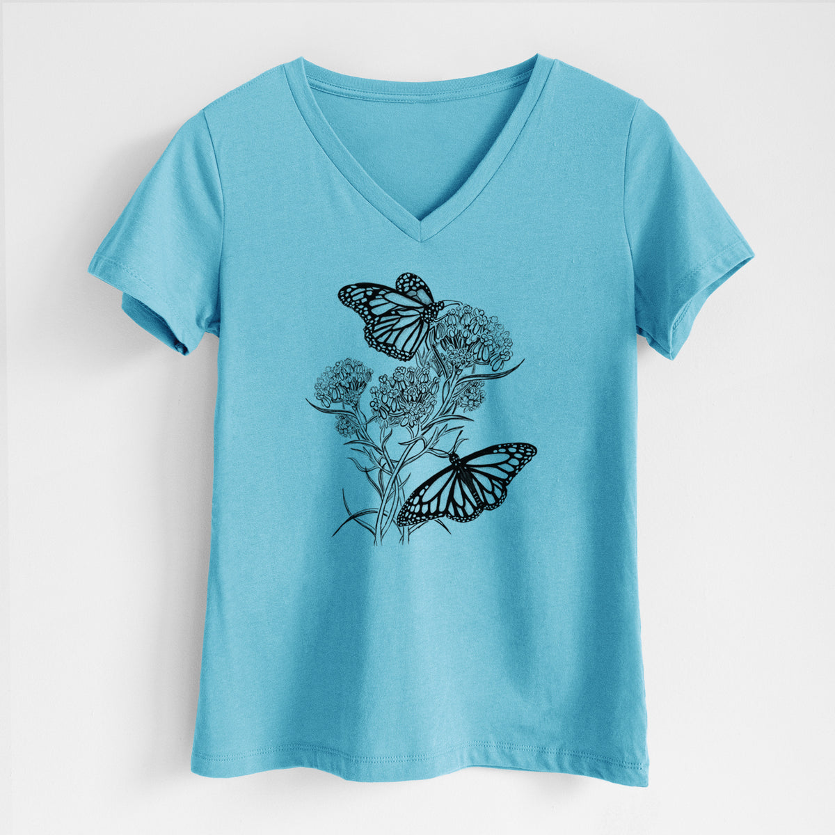 Turquoise women's relaxed fit cotton V-neck t-shirt laid flat, printed with a black ink illustration of two monarch butterflies on flowering milkweed.