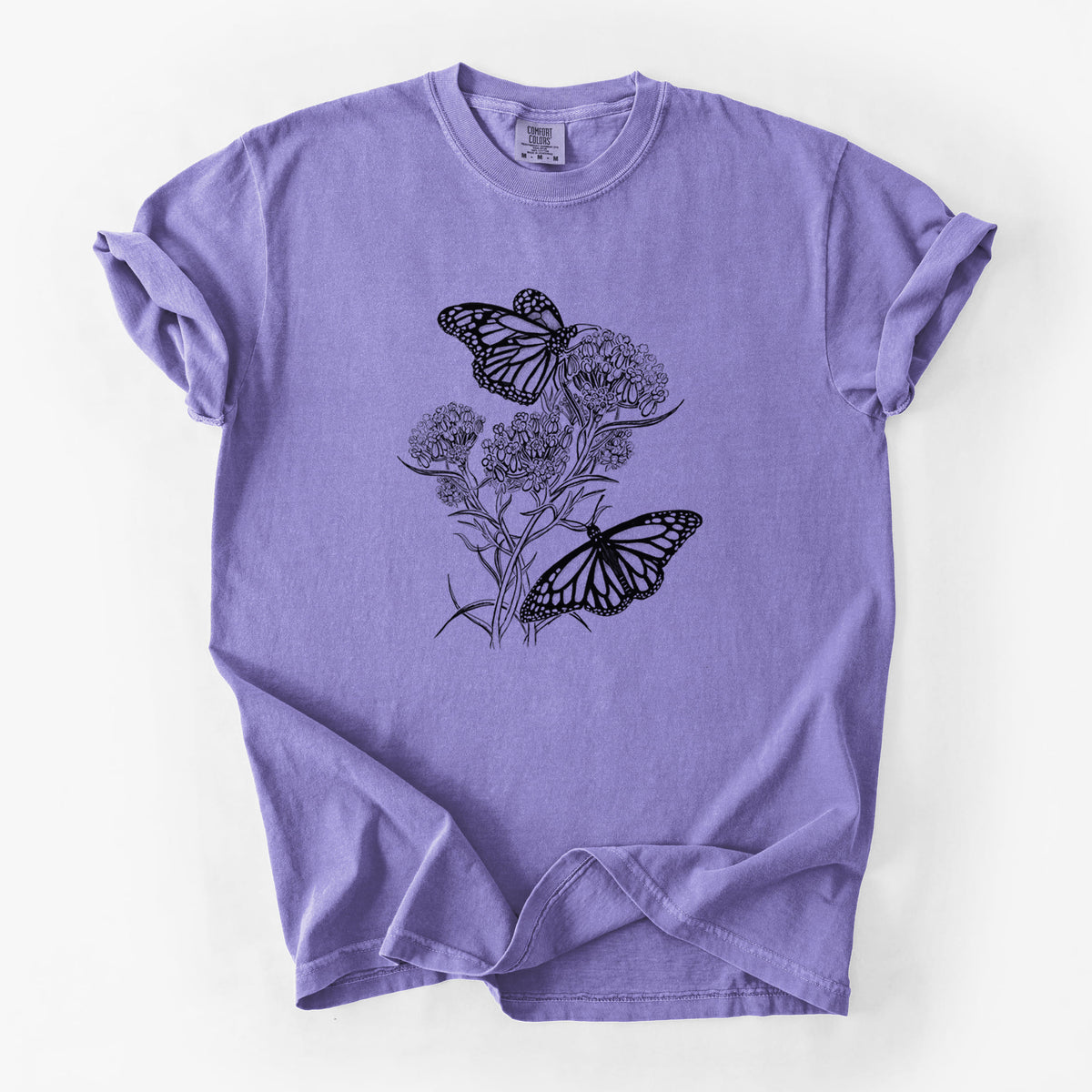 Violet purple Comfort Colors t-shirt laid flat, printed with a black ink illustration of two monarch butterflies on flowering milkweed.