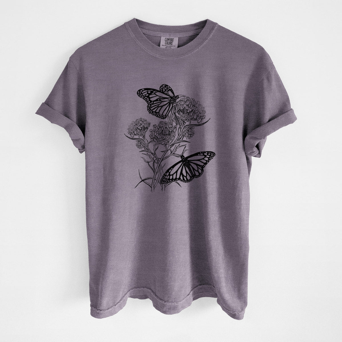 Wine red Comfort Colors t-shirt laid flat, printed with a black ink illustration of two monarch butterflies on flowering milkweed.