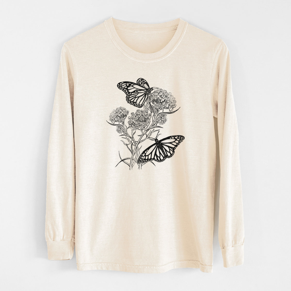 Ivory Comfort Colors long sleeve shirt laid flat, printed with a black ink illustration of two monarch butterflies on flowering milkweed.