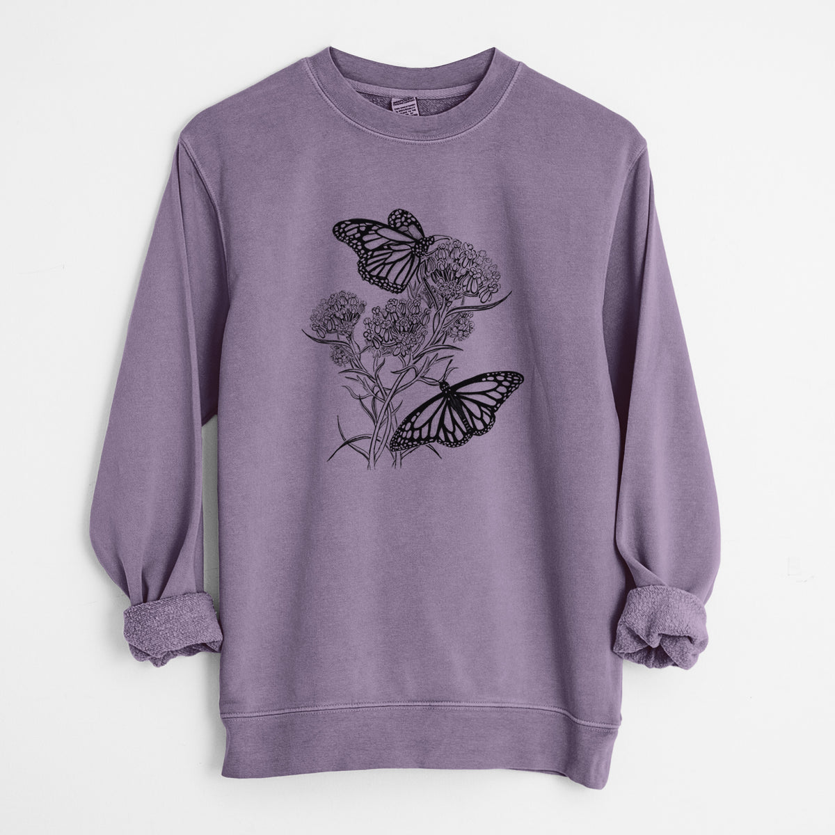 Plum purple pigment dyed crewneck sweatshirt laid flat with the sleeves rolled, printed with a black ink illustration of two monarch butterflies on flowering milkweed.