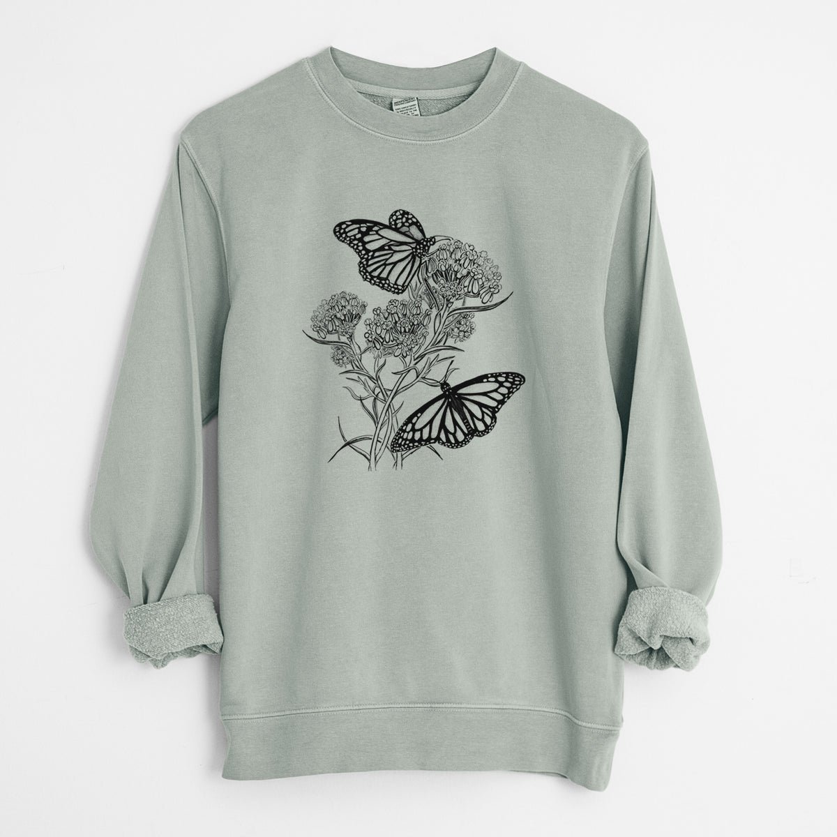 Sage green pigment dyed crewneck sweatshirt laid flat with the sleeves rolled, printed with a black ink illustration of two monarch butterflies on flowering milkweed.