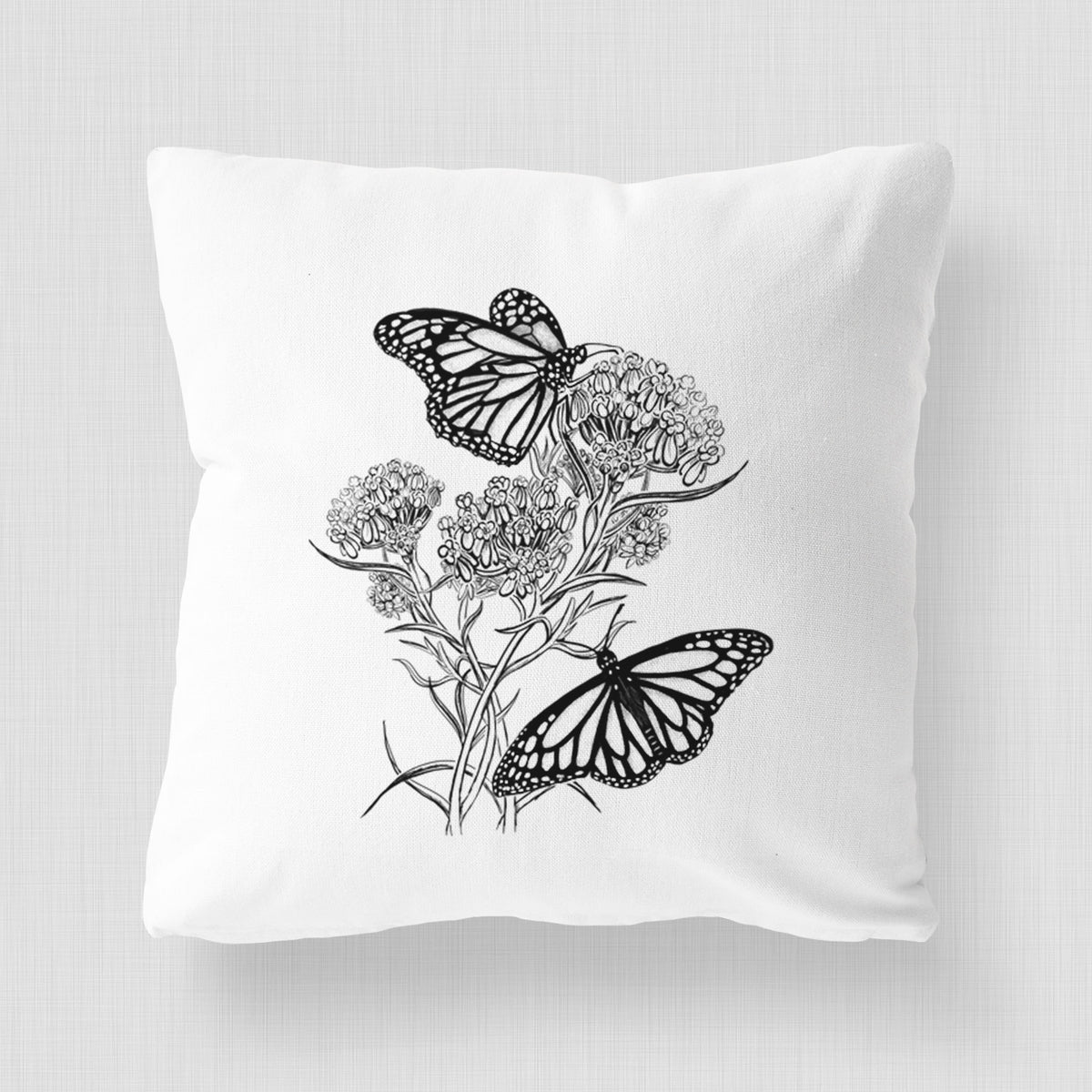 White pillow cover printed with a black ink illustration of two monarch butterflies on flowering milkweed.