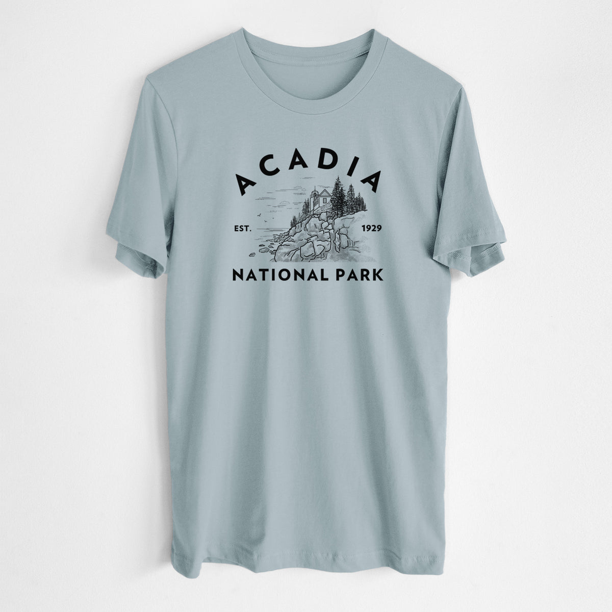 Vintage denim lightweight cotton t-shirt laid flat, printed with a round badge of a rocky coastline and pine trees, with the words Acadia National Park, Est. 1929.