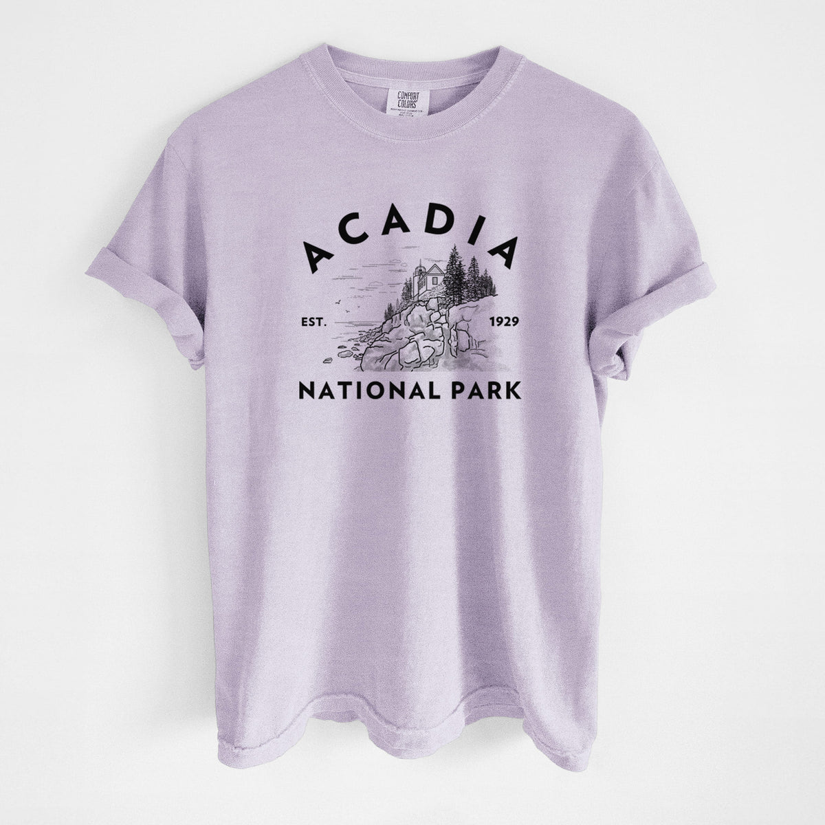 Orchid purple Comfort Colors t-shirt laid flat, printed with a round badge of a rocky coastline and pine trees, with the words Acadia National Park, Est. 1929.