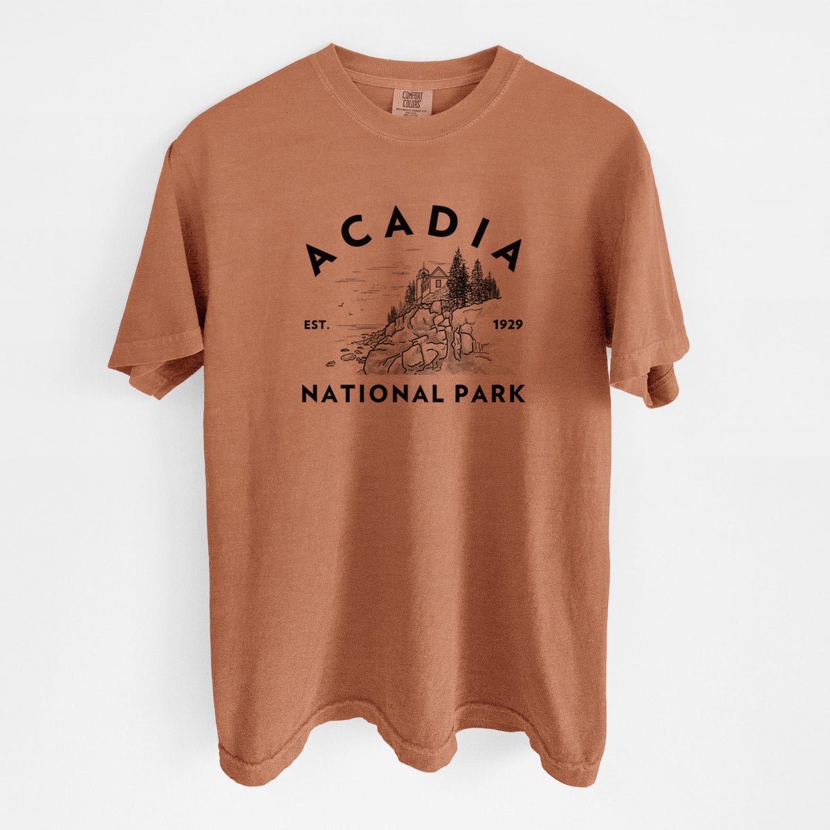 Yam burnt orange Comfort Colors t-shirt laid flat, printed with a round badge of a rocky coastline and pine trees, with the words Acadia National Park, Est. 1929.