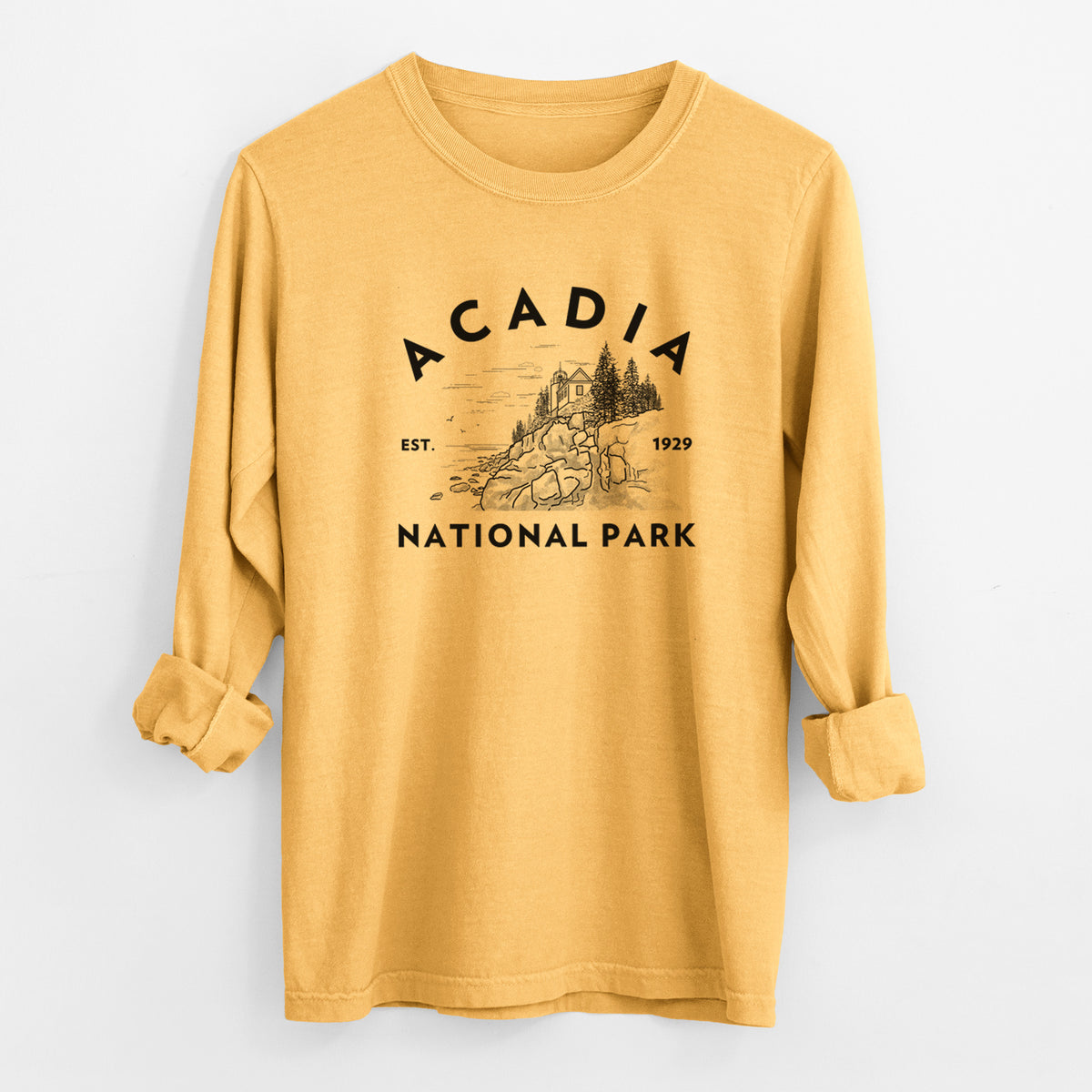Golden wheat yellow Comfort Colors long sleeve shirt laid flat with the cuffs rolled, printed with a round badge of a rocky coastline and pine trees, with the words Acadia National Park, Est. 1929.