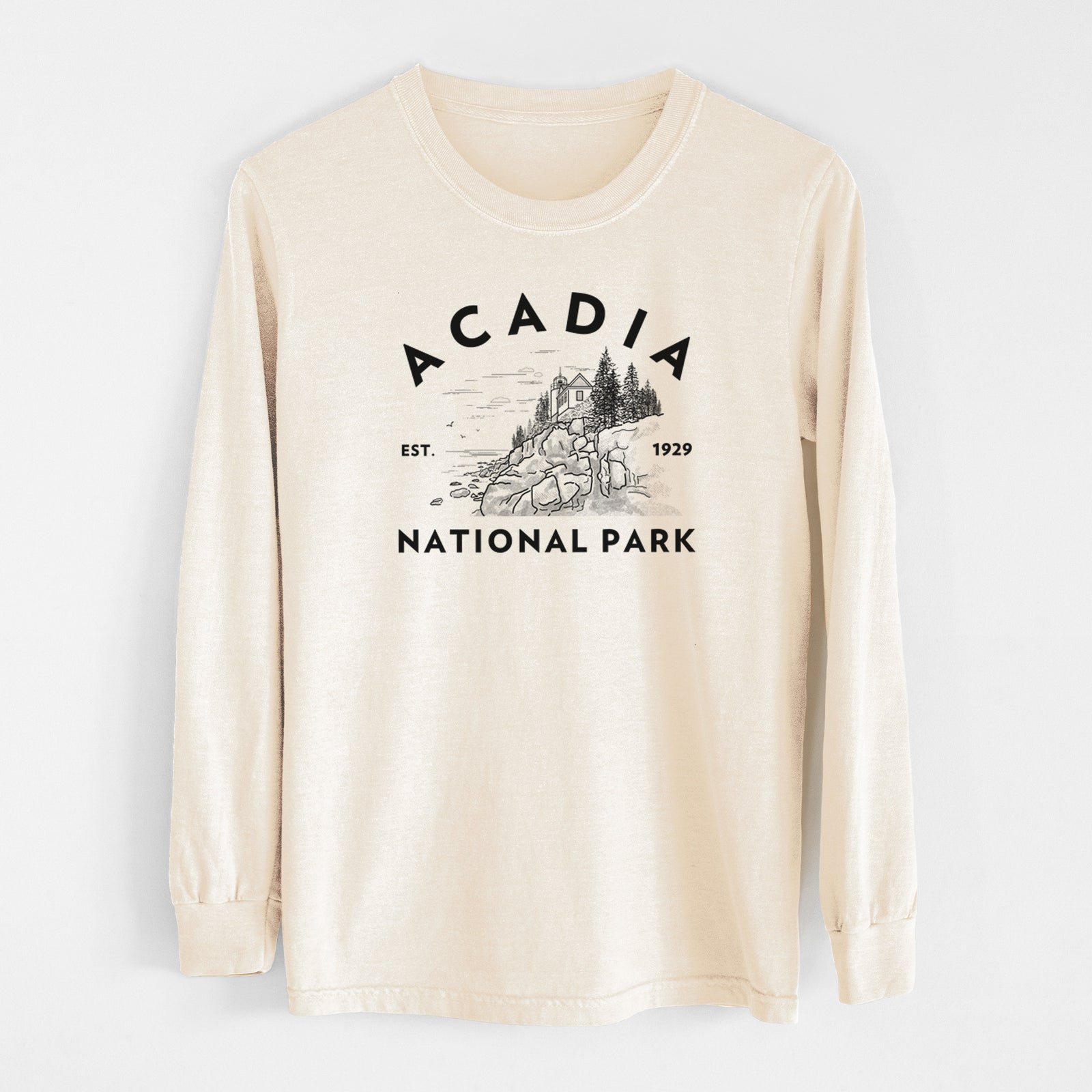 Ivory Comfort Colors long sleeve shirt laid flat, printed with a round badge of a rocky coastline and pine trees, with the words Acadia National Park, Est. 1929.