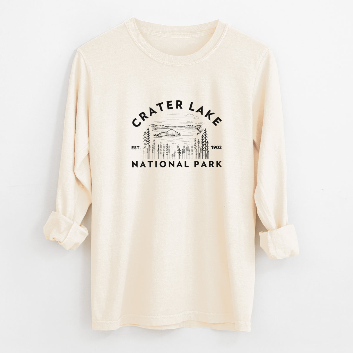 Ivory Comfort Colors long sleeve shirt laid flat with the cuffs rolled, printed with a round badge of Crater Lake ringed by pine trees, with the words Crater Lake National Park, Est. 1902.