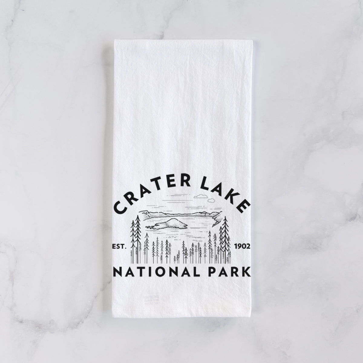 White cotton tea towel laid flat on marble, printed with a round badge of Crater Lake ringed by pine trees, with the words Crater Lake National Park, Est. 1902.