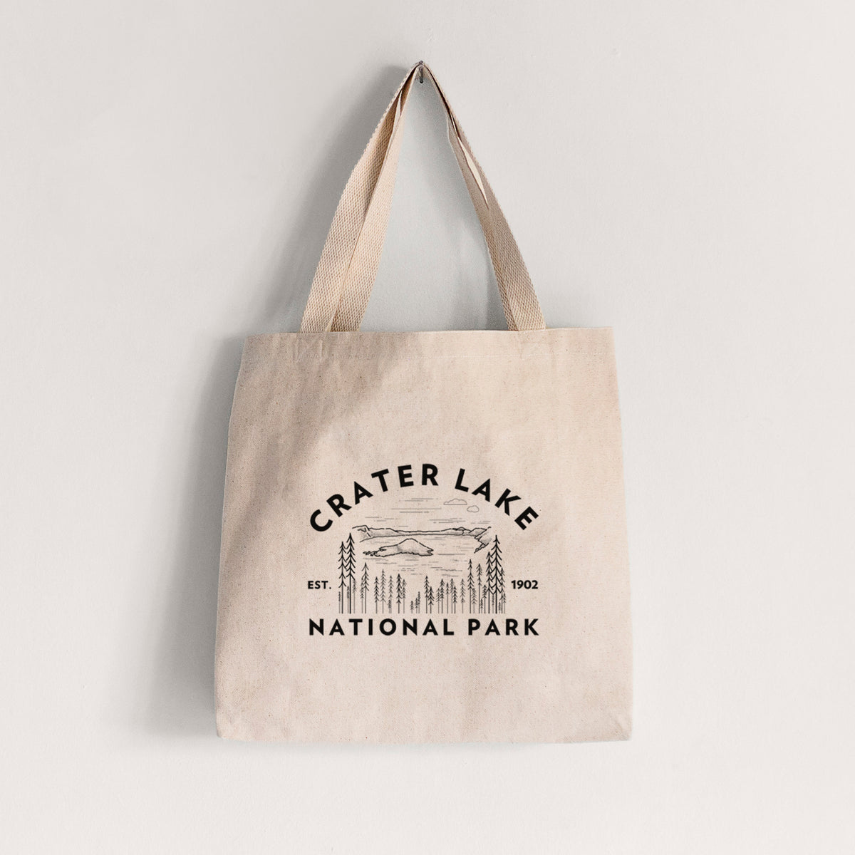 Natural canvas tote bag printed with a round badge of Crater Lake ringed by pine trees, with the words Crater Lake National Park, Est. 1902.