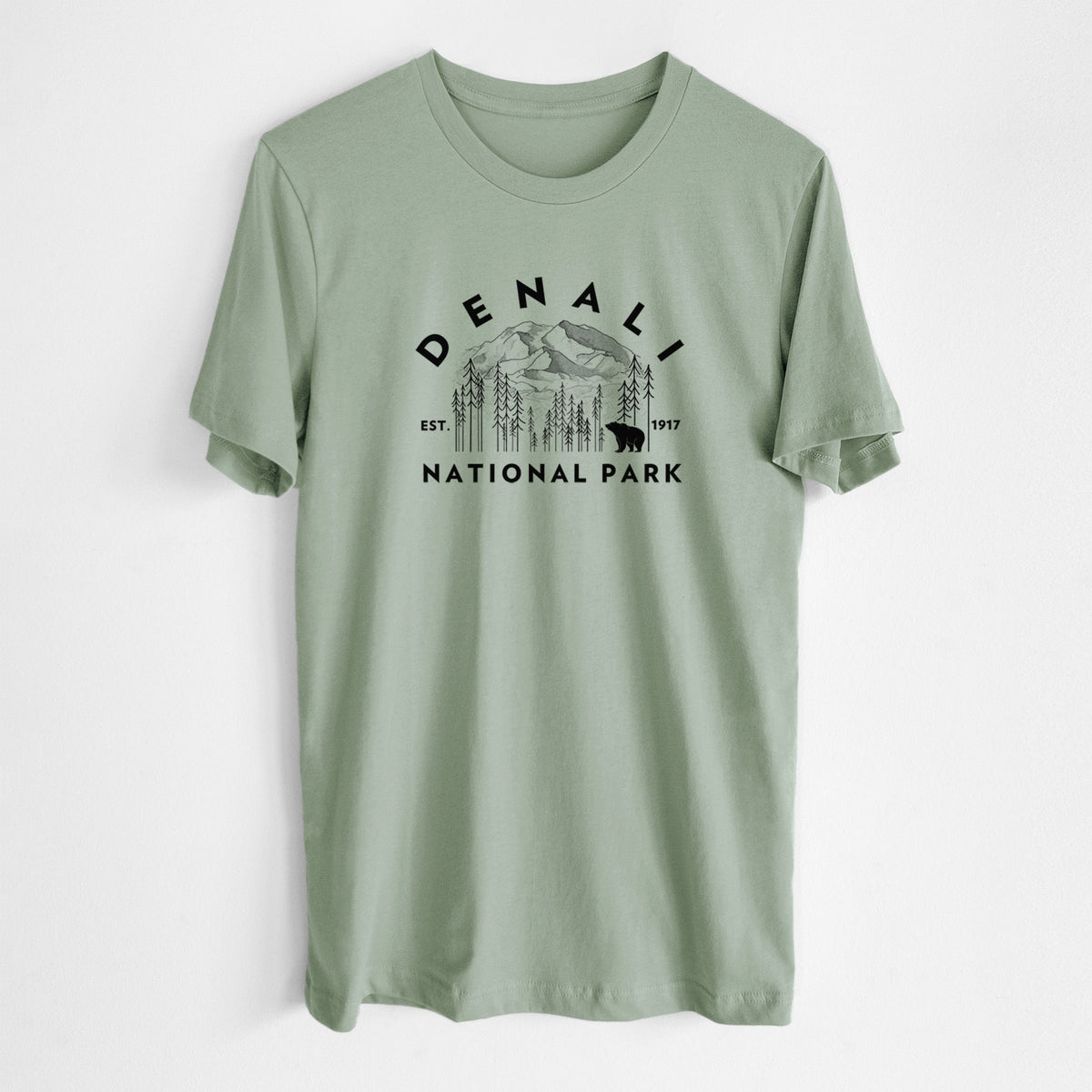Sage green lightweight cotton t-shirt laid flat, printed with a round badge of mountains, pine trees and a bear, with the words Denali National Park, Est. 1917.