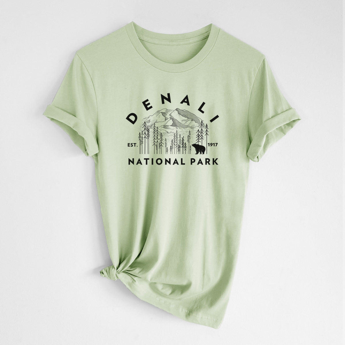 Spring green lightweight cotton t-shirt laid flat with the sleeves rolled, printed with a round badge of mountains, pine trees and a bear, with the words Denali National Park, Est. 1917.