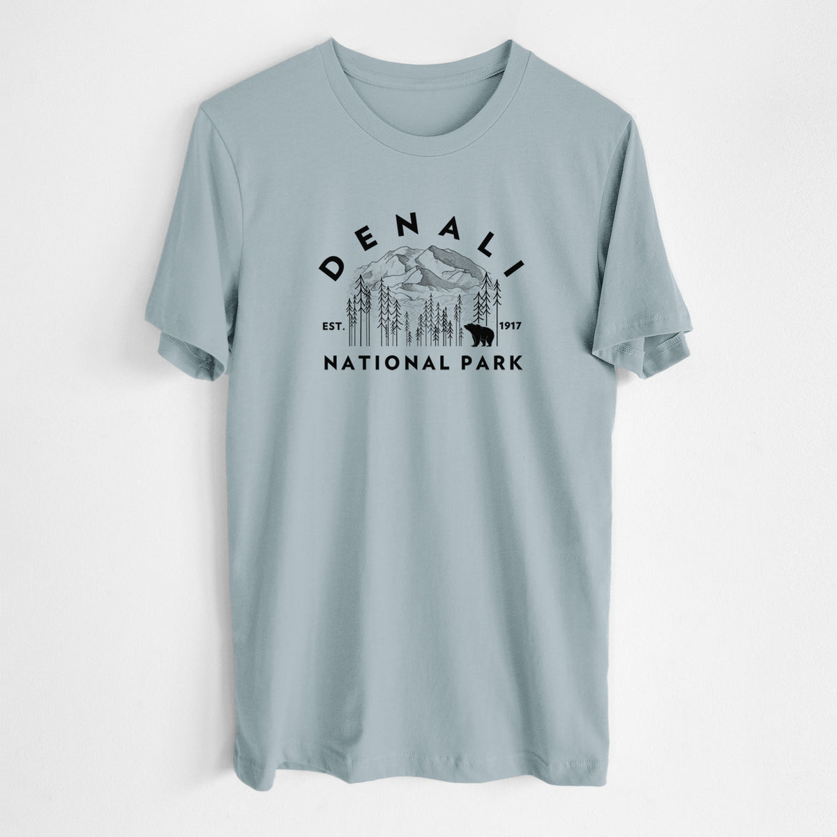 Vintage denim lightweight cotton t-shirt laid flat, printed with a round badge of mountains, pine trees and a bear, with the words Denali National Park, Est. 1917.