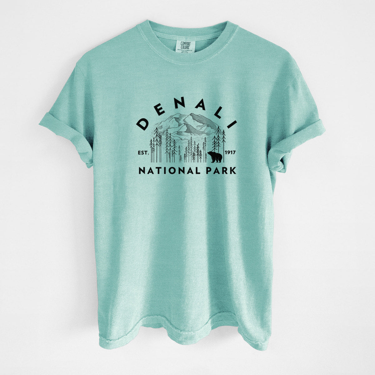 Chalky mint Comfort Colors t-shirt laid flat, printed with a round badge of mountains, pine trees and a bear, with the words Denali National Park, Est. 1917.