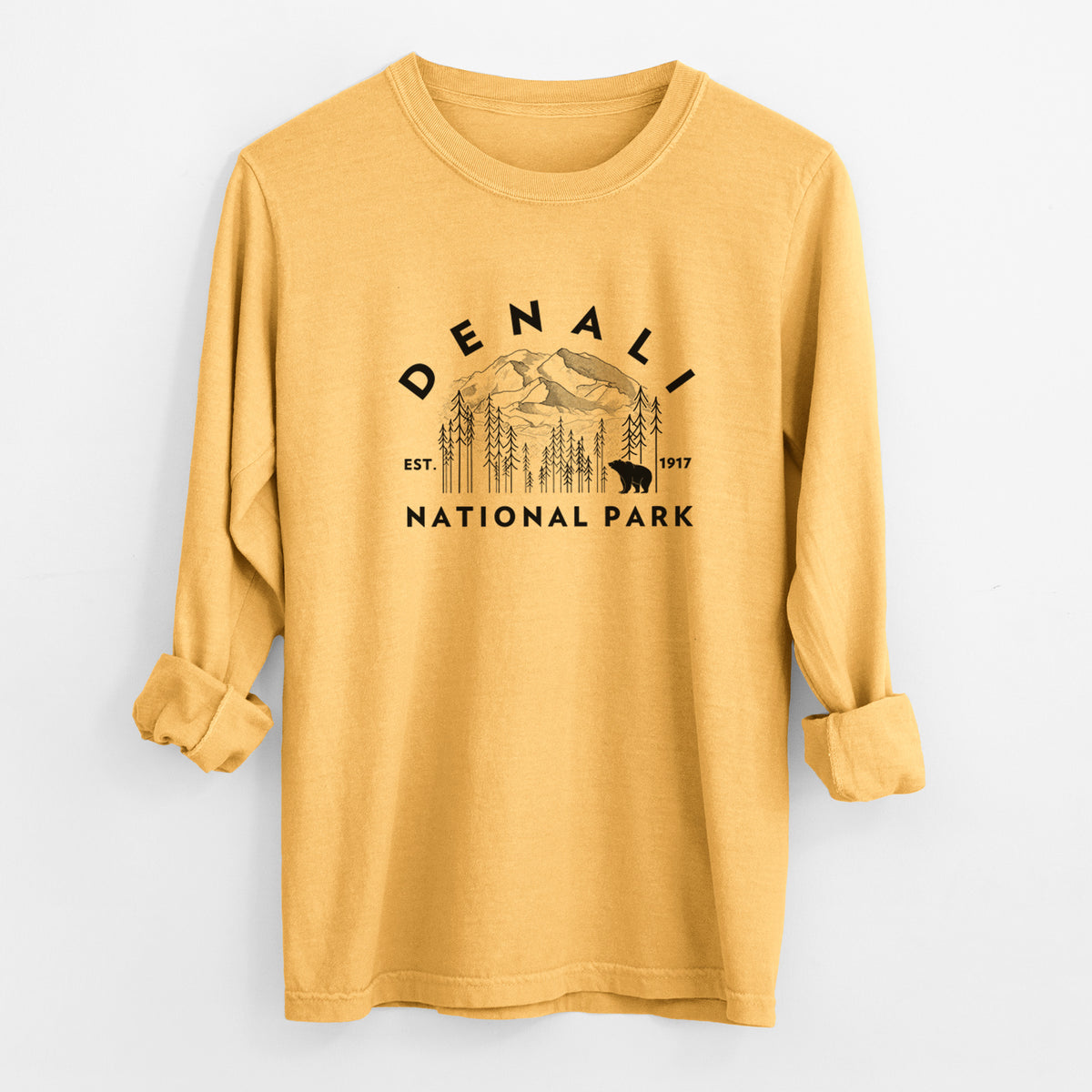 Golden wheat yellow Comfort Colors long sleeve shirt laid flat with the cuffs rolled, printed with a round badge of mountains, pine trees and a bear, with the words Denali National Park, Est. 1917.