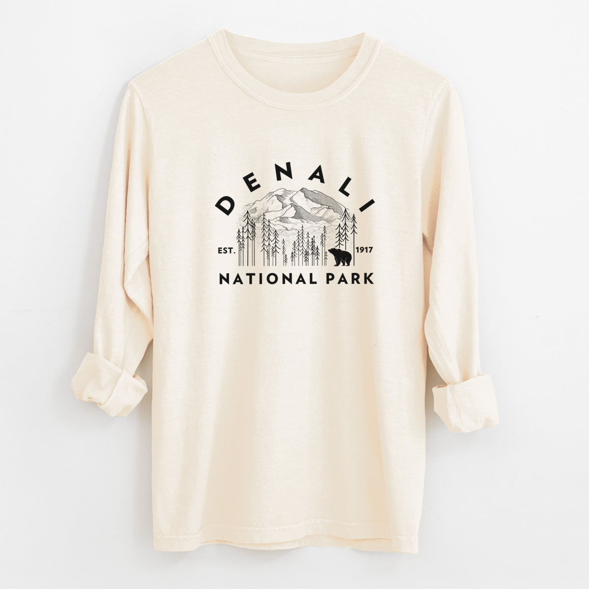Ivory Comfort Colors long sleeve shirt laid flat with the cuffs rolled, printed with a round badge of mountains, pine trees and a bear, with the words Denali National Park, Est. 1917.