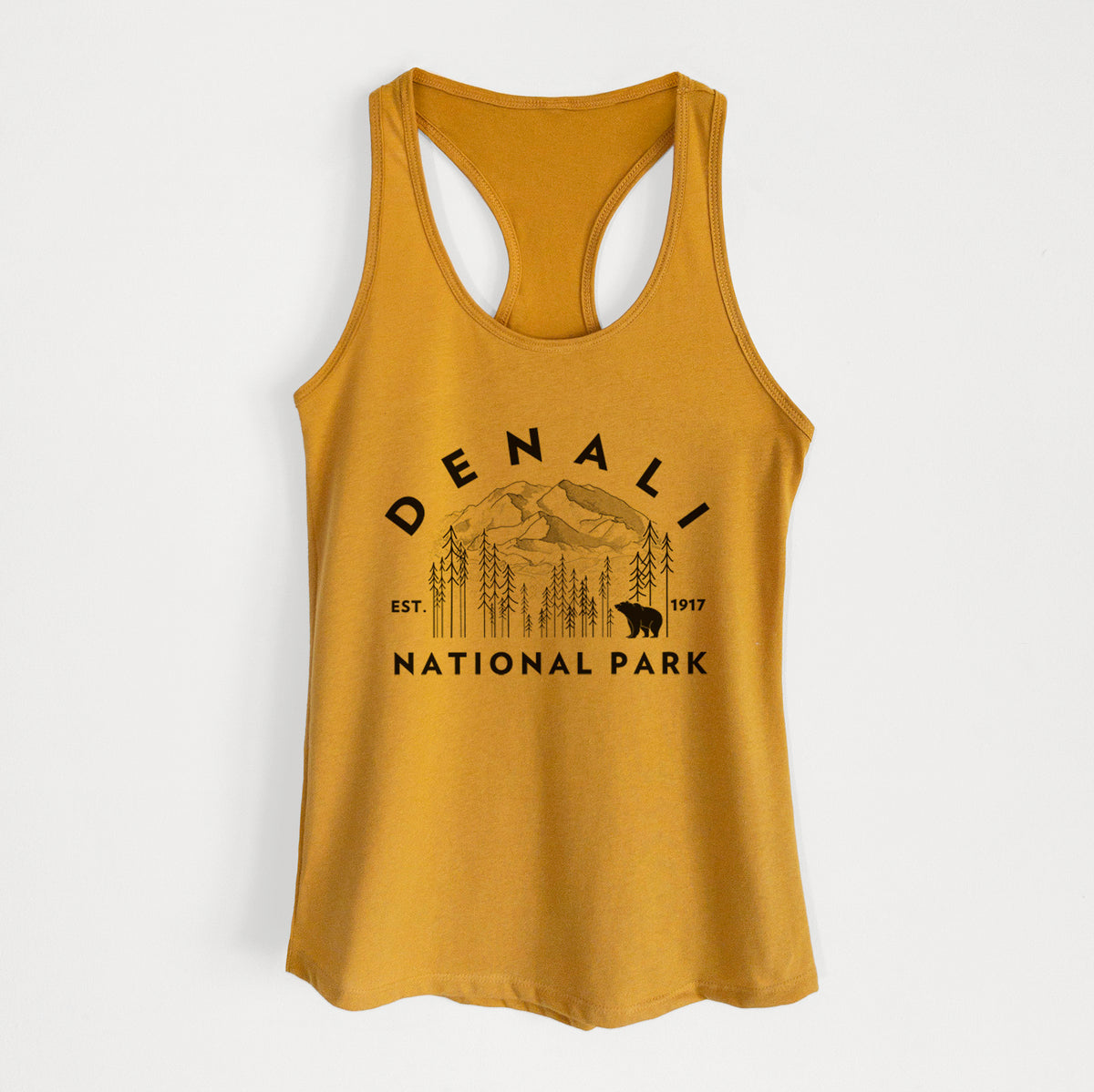Gold women's racerback tank top laid flat, printed with a round badge of mountains, pine trees and a bear, with the words Denali National Park, Est. 1917.