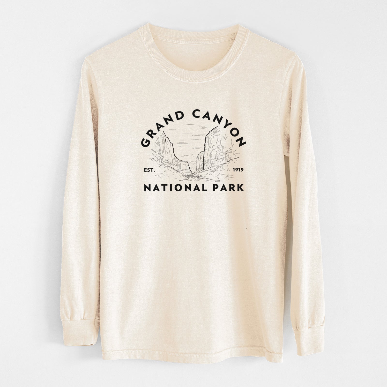 Ivory Comfort Colors long sleeve shirt laid flat, printed with a round badge of canyon cliffs, with the words Grand Canyon National Park, Est. 1919.