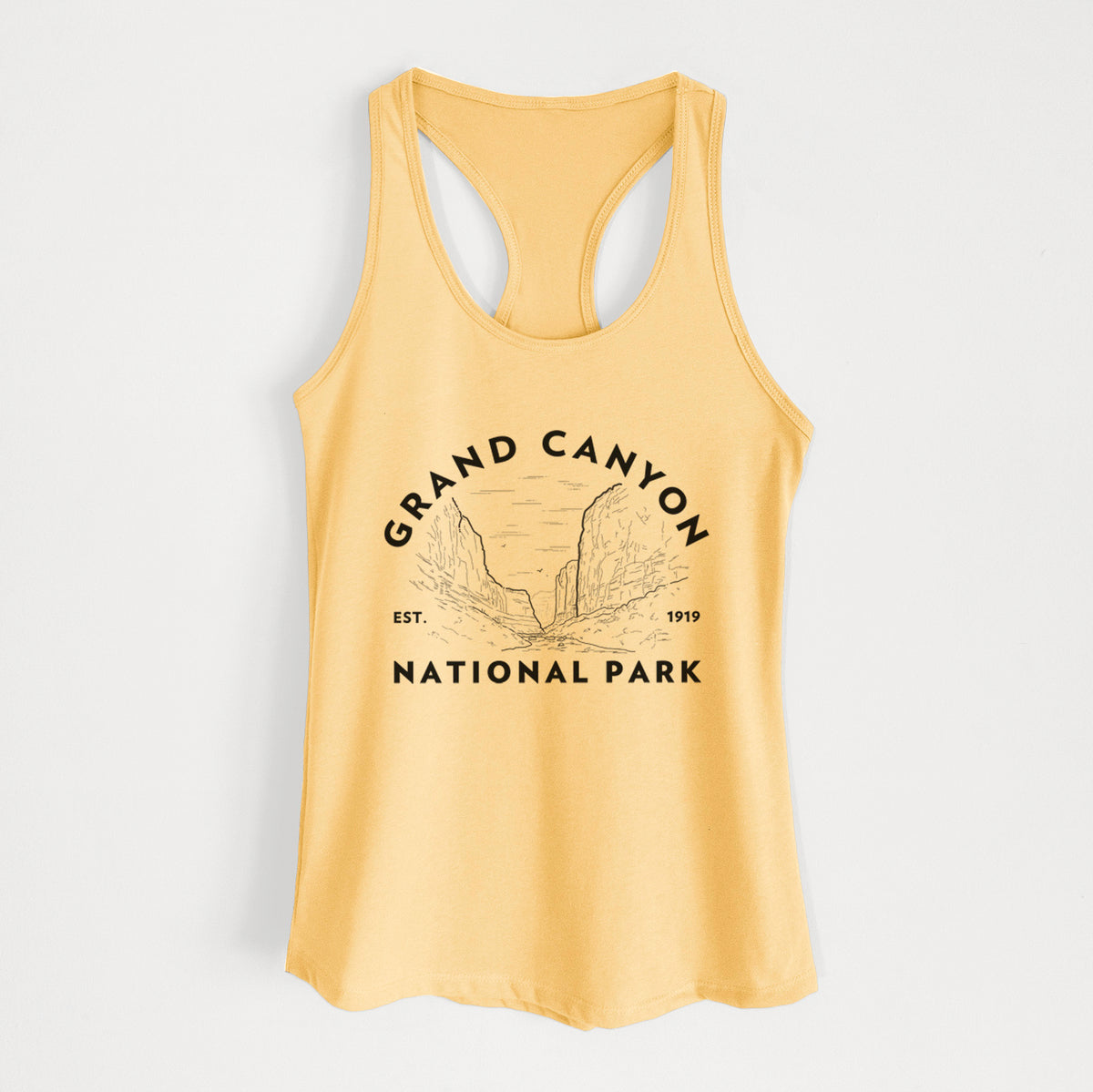 Banana cream women's racerback tank top laid flat, printed with a round badge of canyon cliffs, with the words Grand Canyon National Park, Est. 1919.