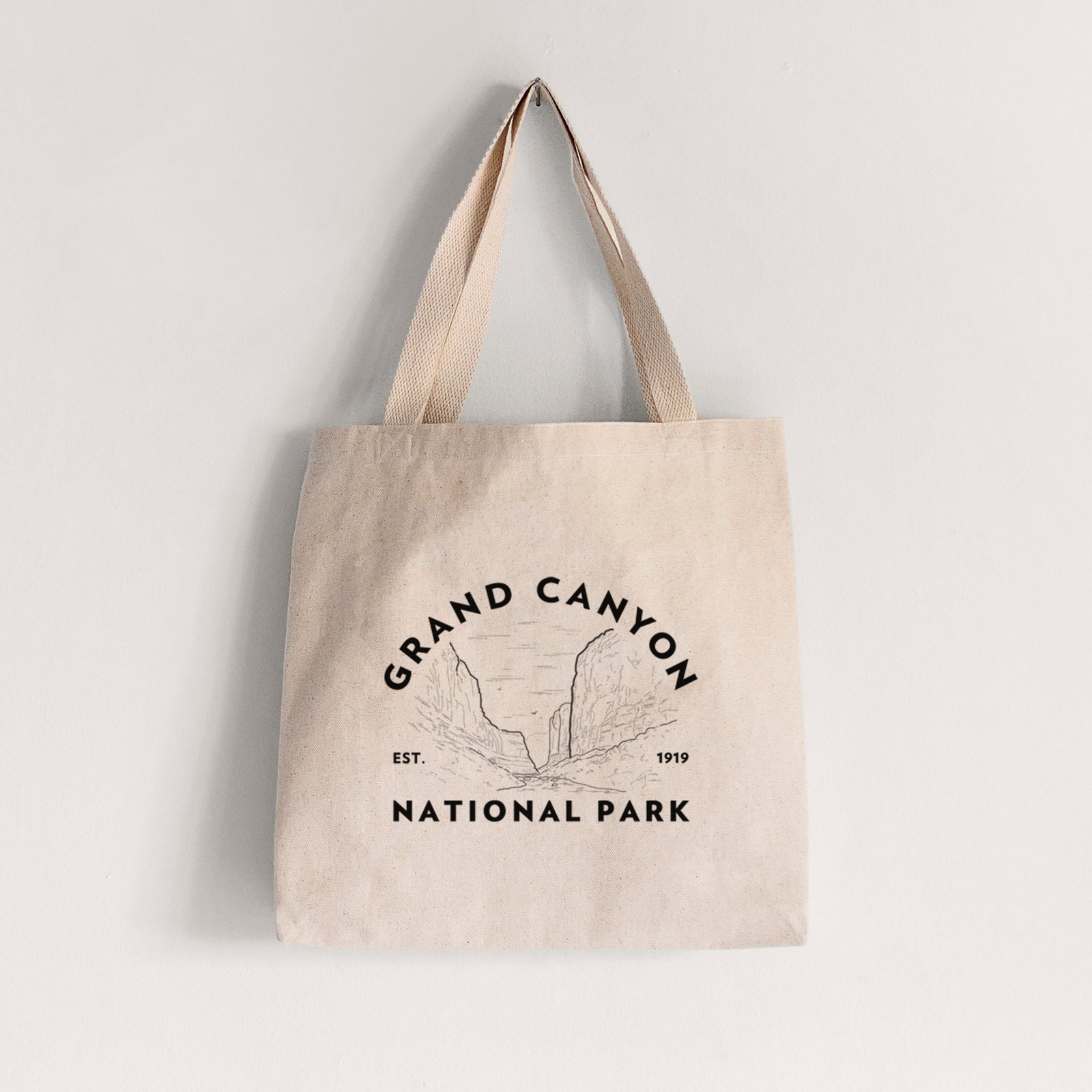 Natural canvas tote bag printed with a round badge of canyon cliffs, with the words Grand Canyon National Park, Est. 1919.