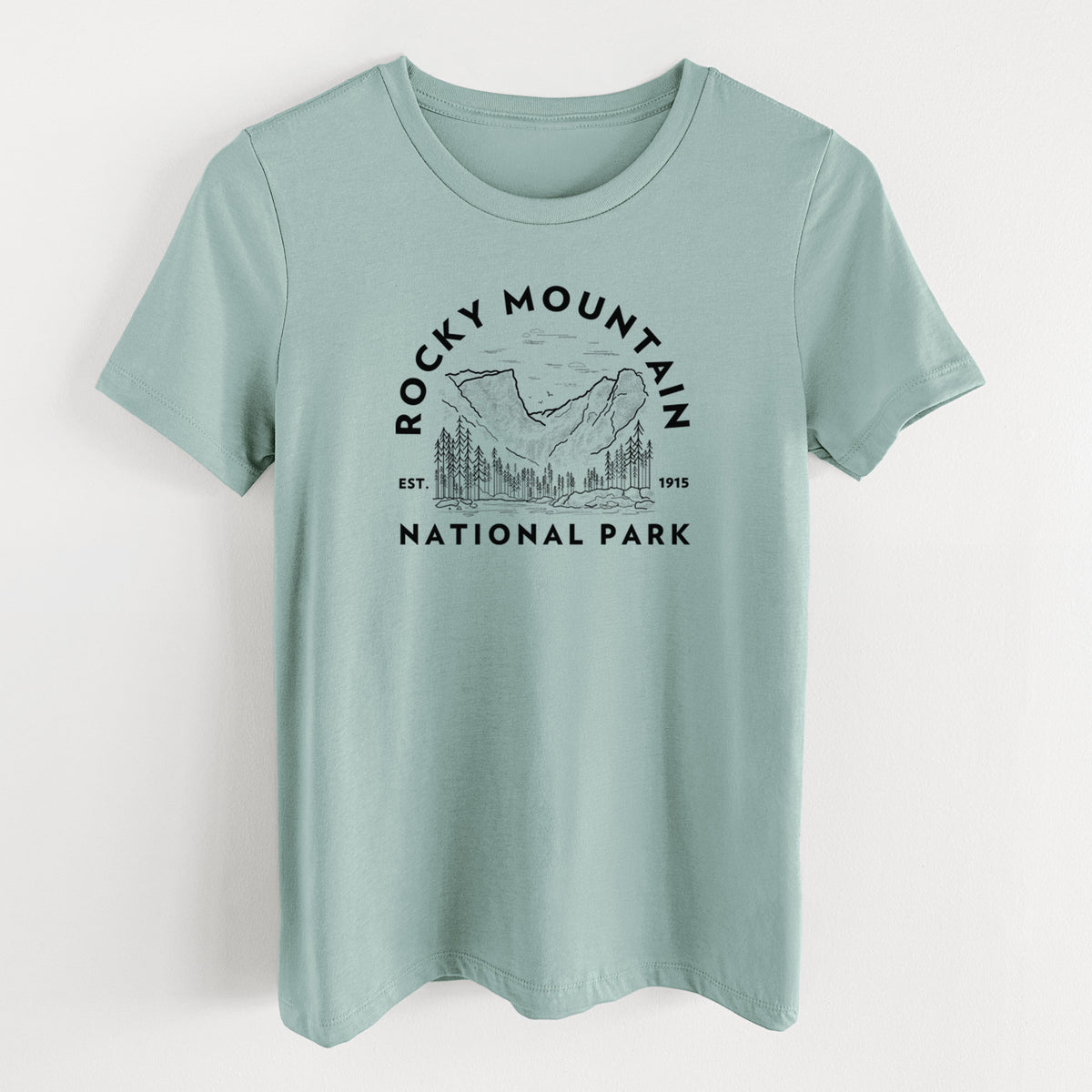 Dusty blue women's relaxed fit cotton t-shirt laid flat, printed with a round badge of mountains and pine trees, with the words Rocky Mountain National Park, Est. 1915.
