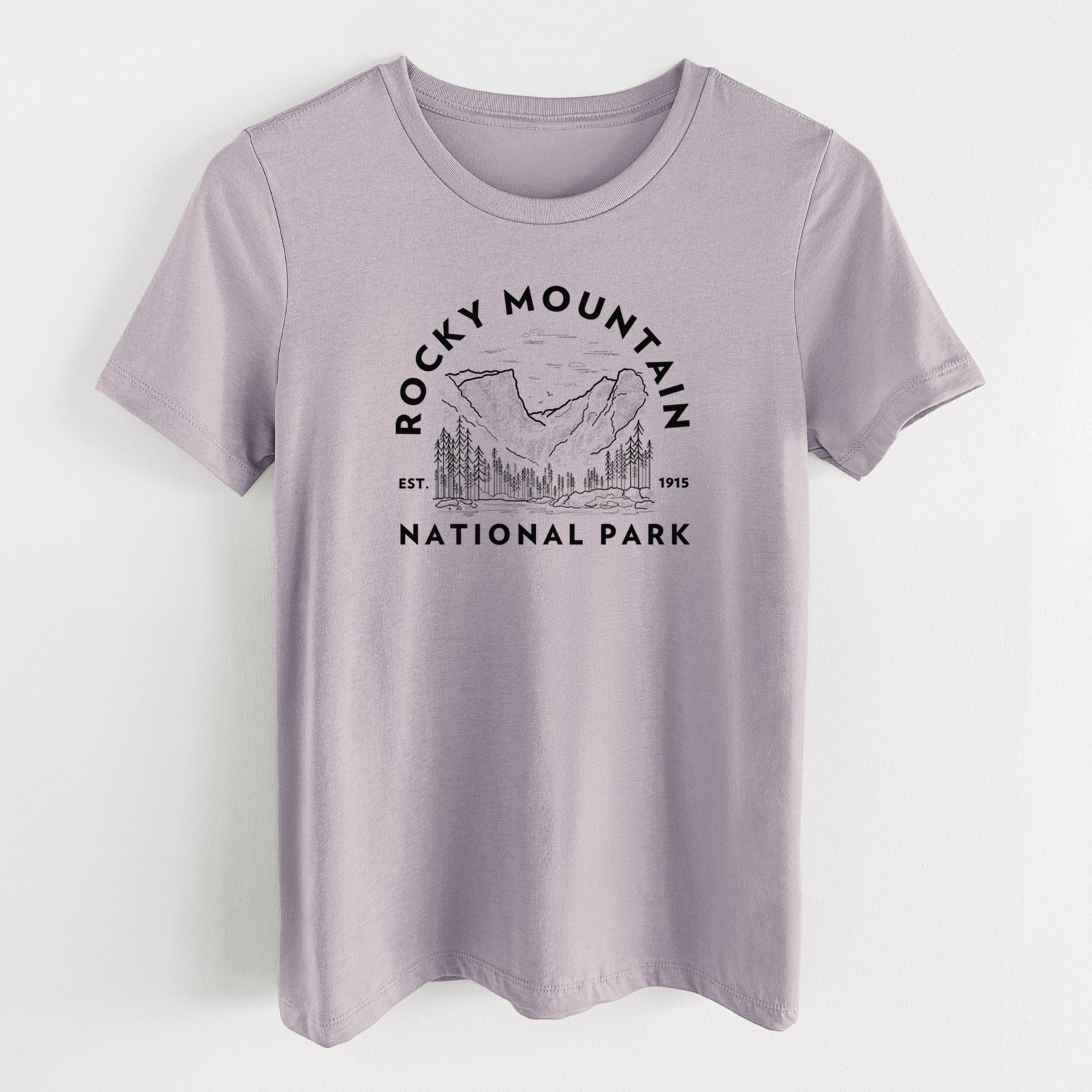 Light violet women's relaxed fit cotton t-shirt laid flat, printed with a round badge of mountains and pine trees, with the words Rocky Mountain National Park, Est. 1915.