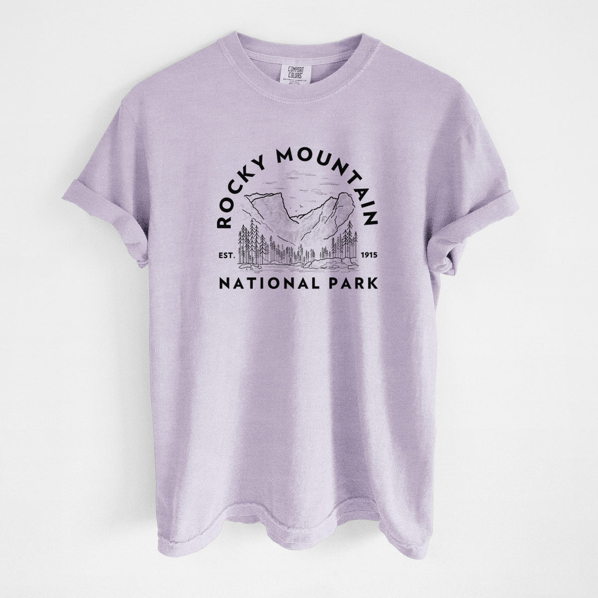 Orchid purple Comfort Colors t-shirt laid flat, printed with a round badge of mountains and pine trees, with the words Rocky Mountain National Park, Est. 1915.
