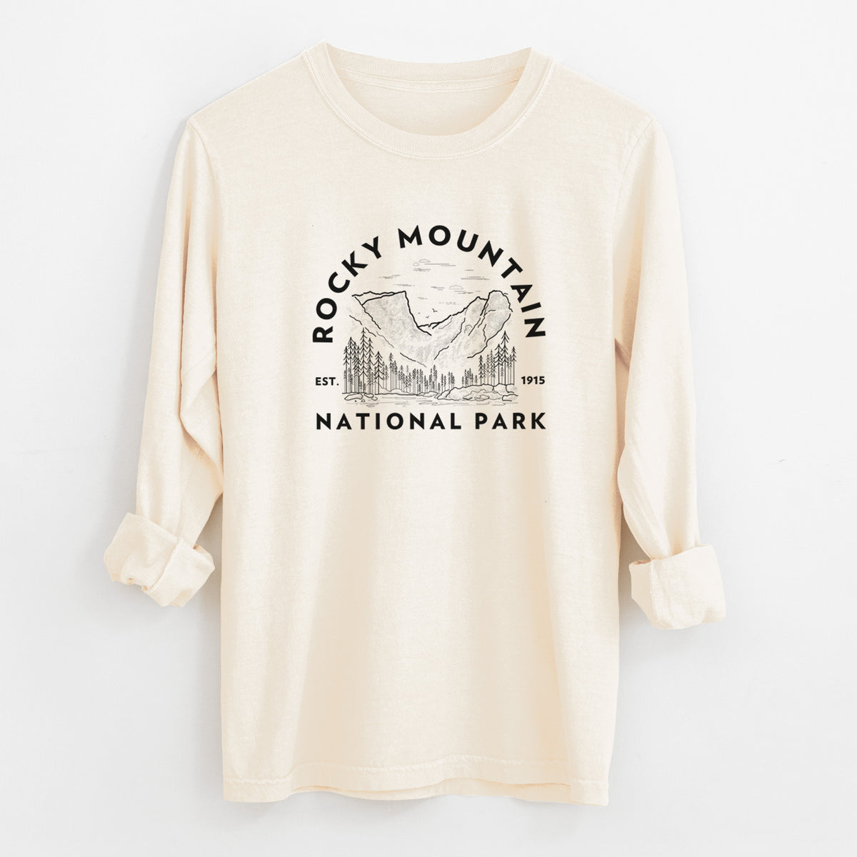 Ivory Comfort Colors long sleeve shirt laid flat with the cuffs rolled, printed with a round badge of mountains and pine trees, with the words Rocky Mountain National Park, Est. 1915.
