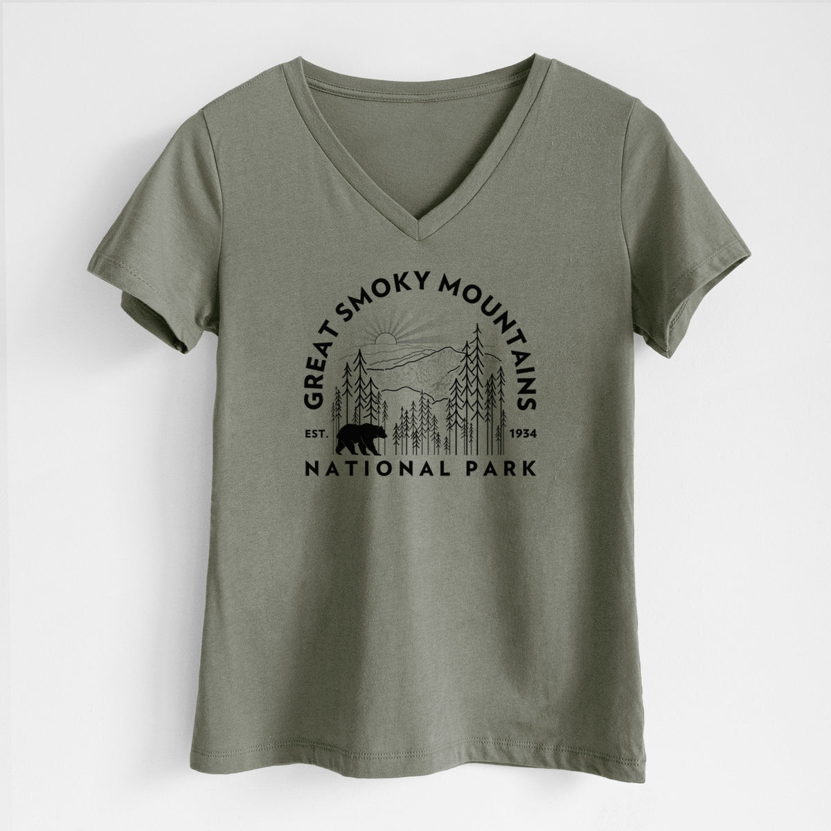 Military green women's relaxed fit cotton V-neck t-shirt laid flat, printed with a round badge of mountains, pine trees and a black bear, with the words Great Smoky Mountains National Park, Est. 1934.