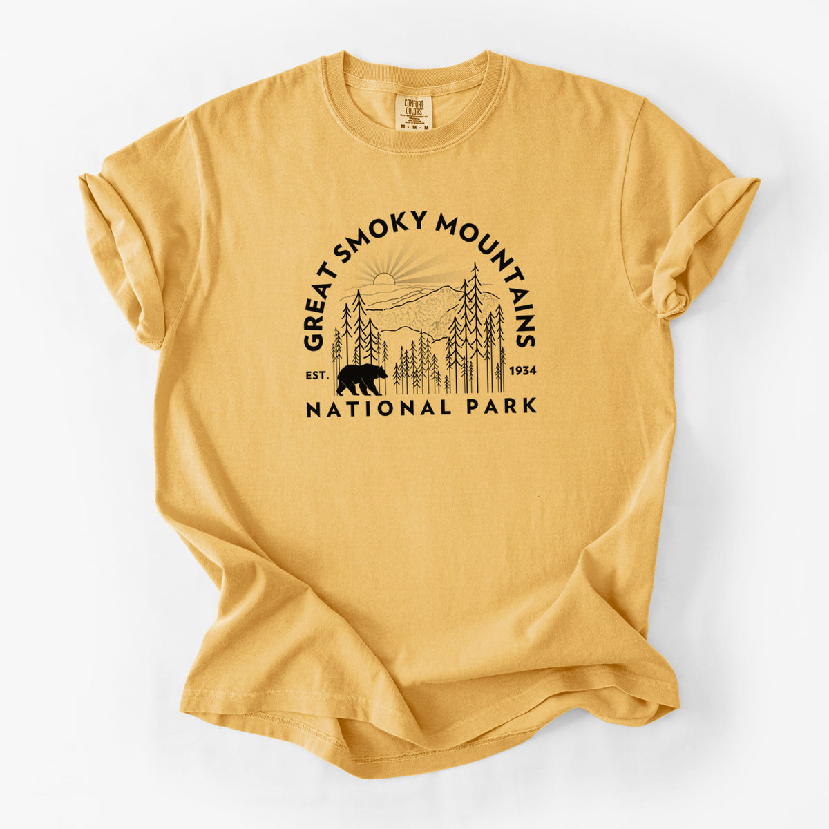 Golden wheat yellow Comfort Colors t-shirt laid flat, printed with a round badge of mountains, pine trees and a black bear, with the words Great Smoky Mountains National Park, Est. 1934.