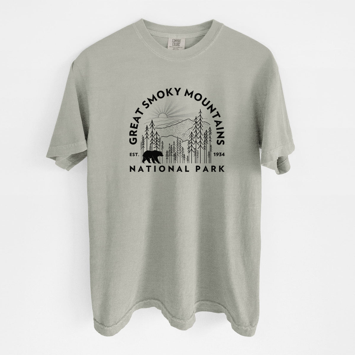 Sandstone beige Comfort Colors t-shirt laid flat, printed with a round badge of mountains, pine trees and a black bear, with the words Great Smoky Mountains National Park, Est. 1934.