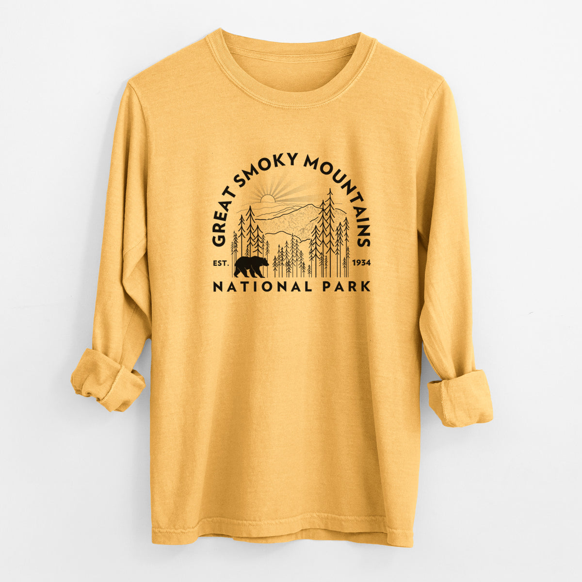 Golden wheat yellow Comfort Colors long sleeve shirt laid flat with the cuffs rolled, printed with a round badge of mountains, pine trees and a black bear, with the words Great Smoky Mountains National Park, Est. 1934.