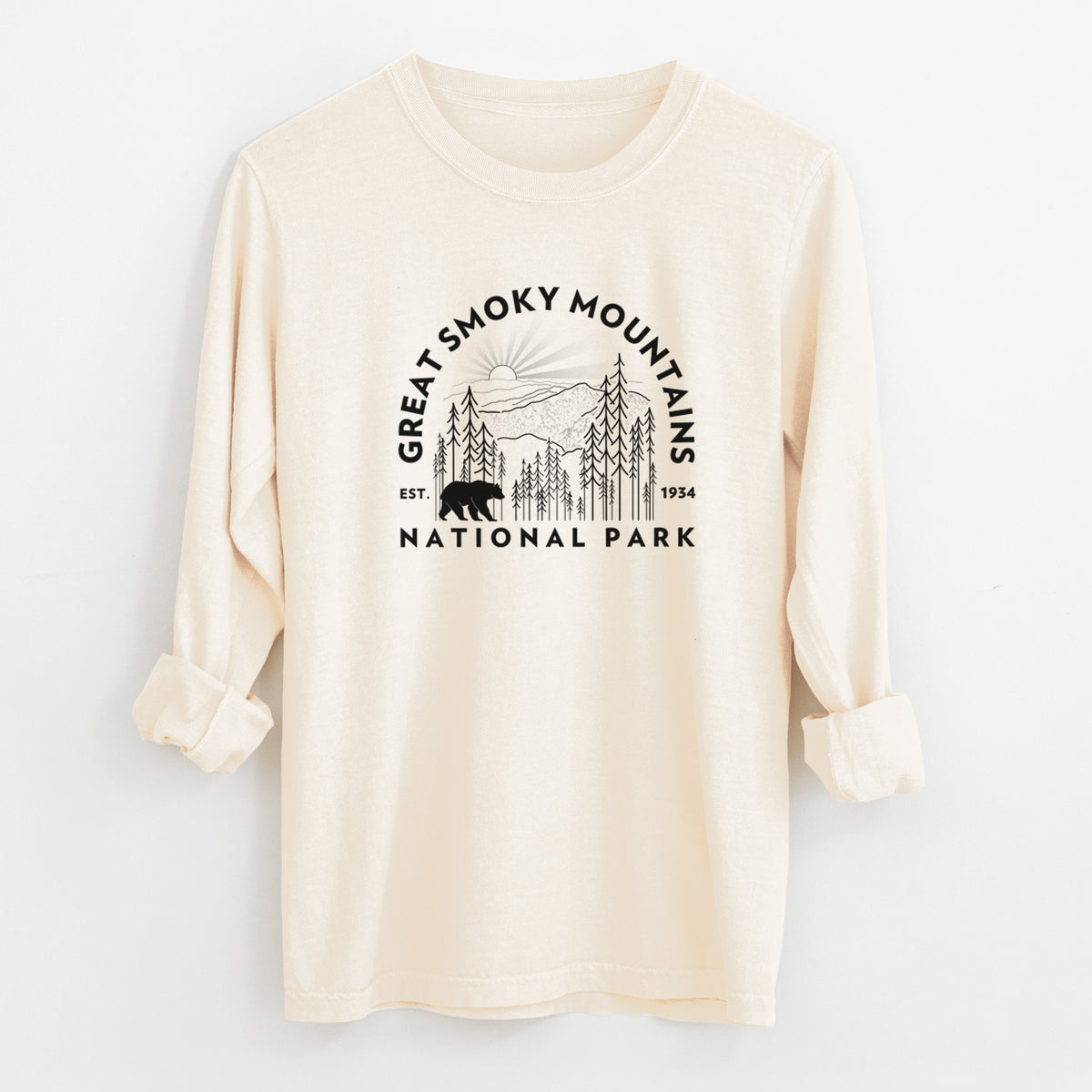 Ivory Comfort Colors long sleeve shirt laid flat with the cuffs rolled, printed with a round badge of mountains, pine trees and a black bear, with the words Great Smoky Mountains National Park, Est. 1934.