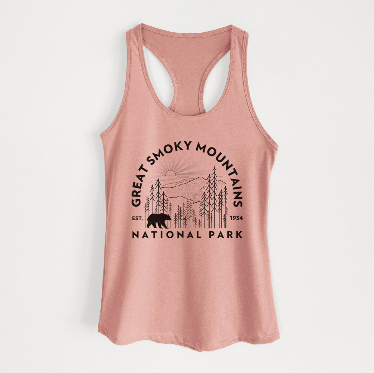 Desert pink women's racerback tank top laid flat, printed with a round badge of mountains, pine trees and a black bear, with the words Great Smoky Mountains National Park, Est. 1934.