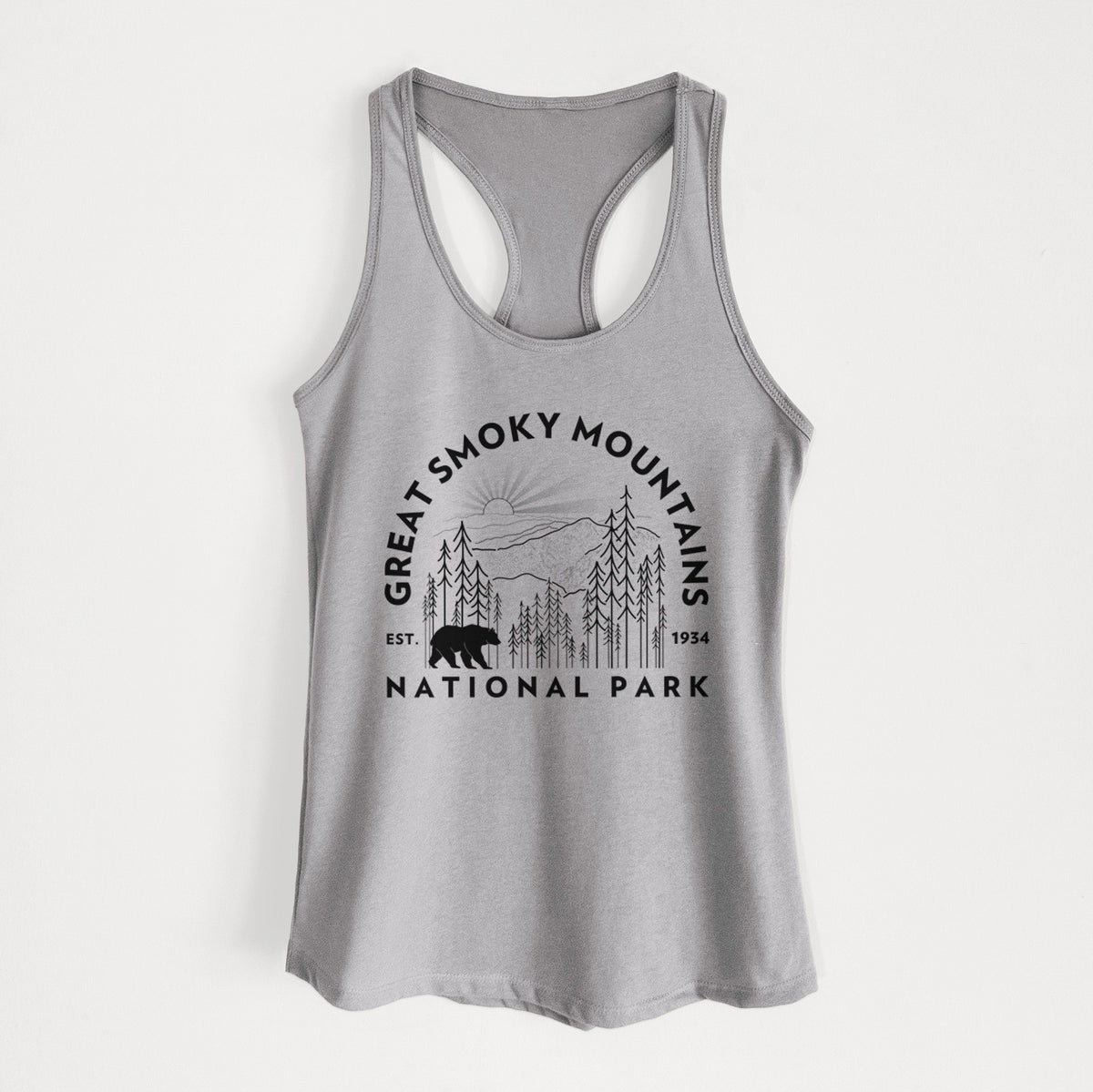 Heather grey women's racerback tank top laid flat, printed with a round badge of mountains, pine trees and a black bear, with the words Great Smoky Mountains National Park, Est. 1934.