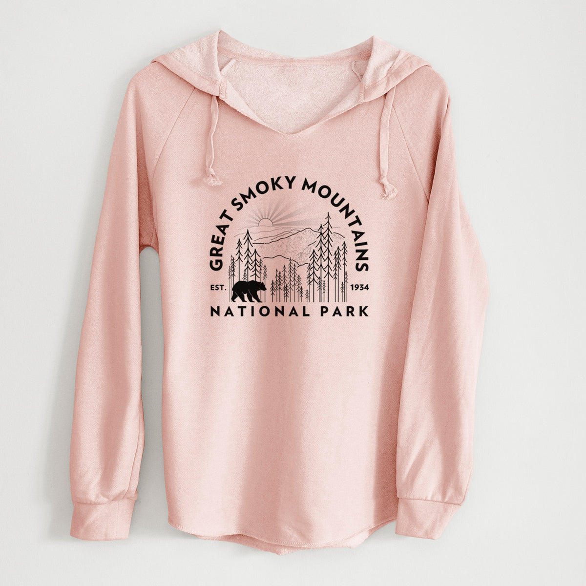Blush pink women's Cali Wave hooded sweatshirt laid flat, printed with a round badge of mountains, pine trees and a black bear, with the words Great Smoky Mountains National Park, Est. 1934.