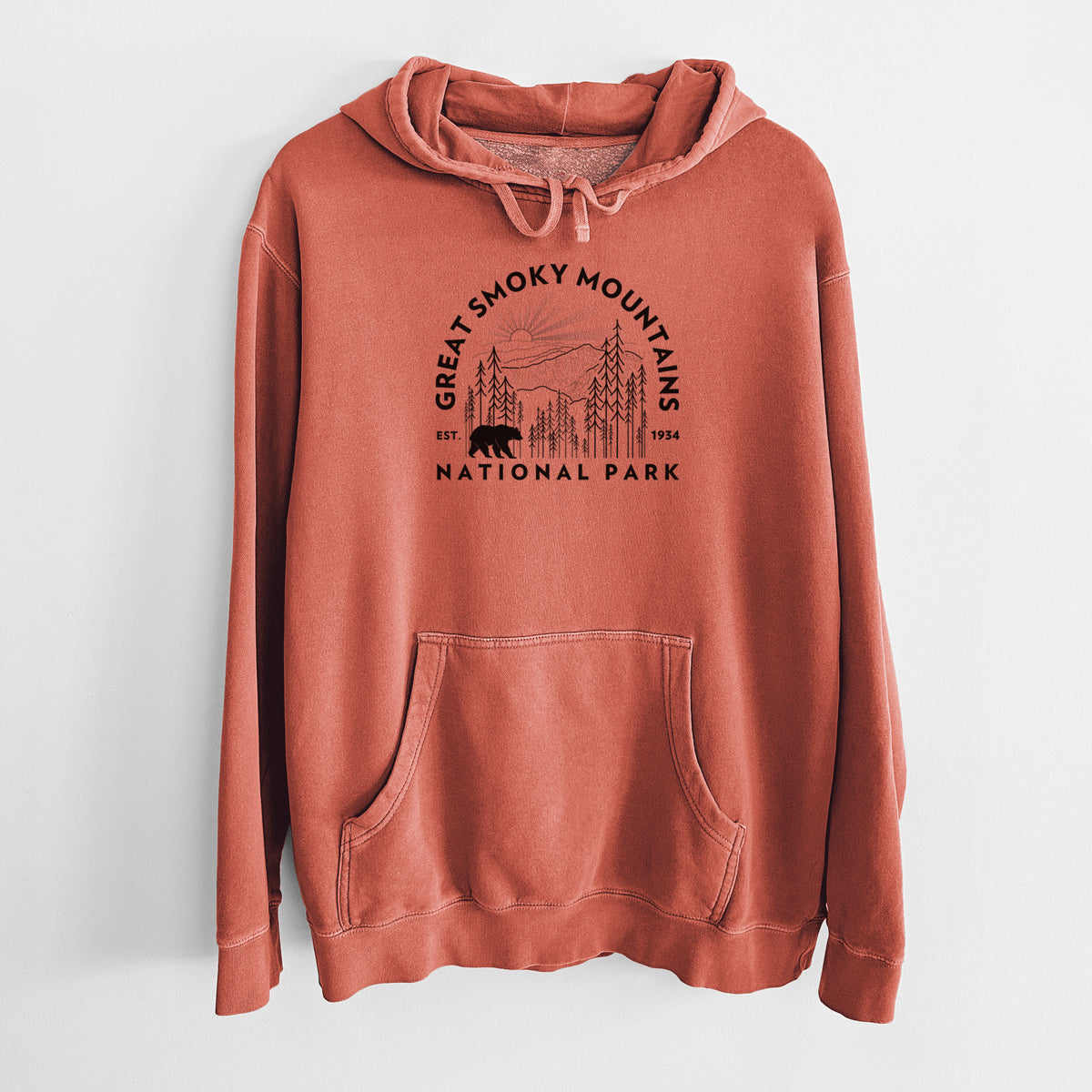Amber orange pigment dyed hoodie laid flat, printed with a round badge of mountains, pine trees and a black bear, with the words Great Smoky Mountains National Park, Est. 1934.